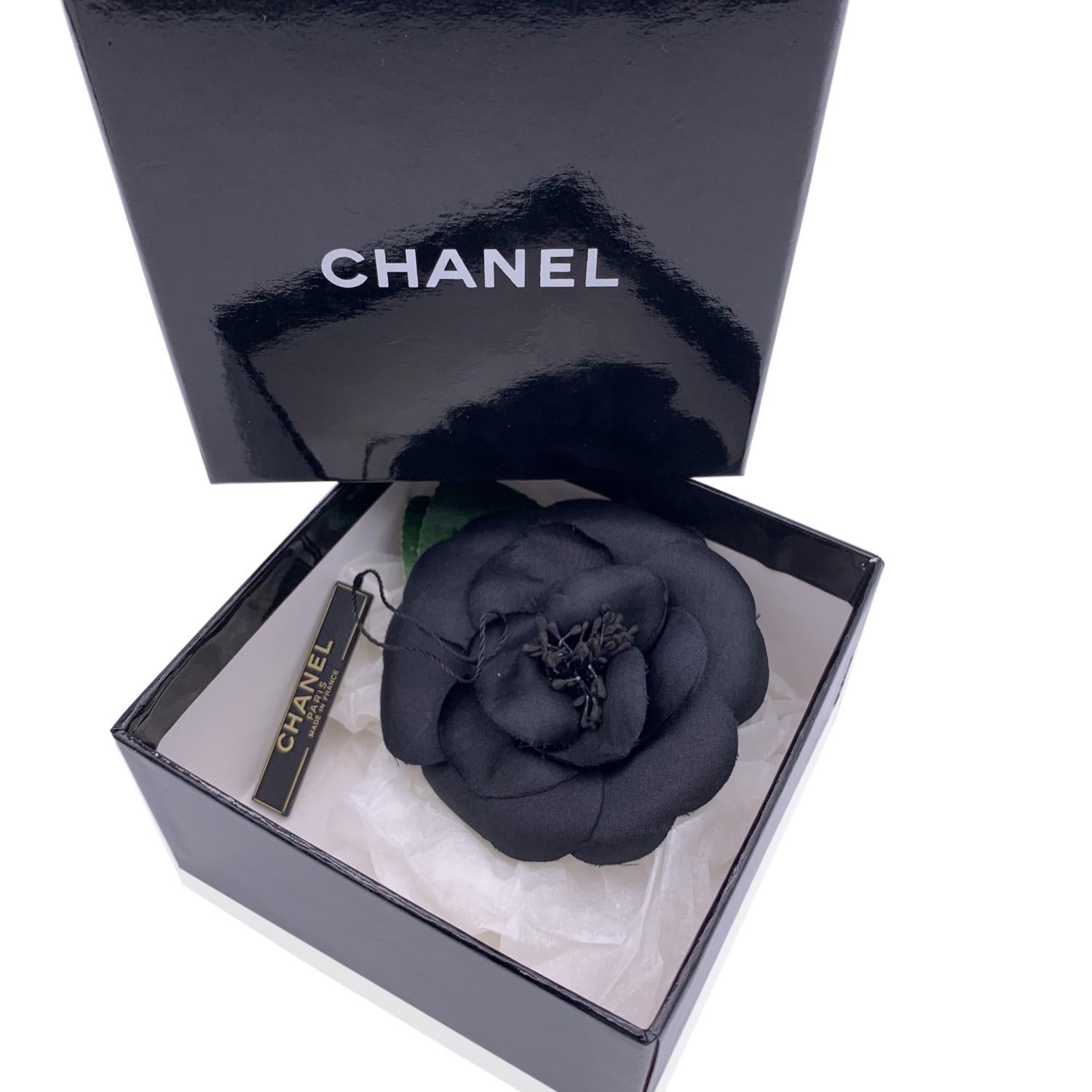 Chanel Vintage Camelia Kamelie Blume Pin Brosche. Blütenblätter aus schwarzem Seidensatin und grüne Blätter aus Stoff. Verschluss mit Sicherheitsnadel. Maße: Durchmesser: 3,5 Zoll - 8,9 cm. ovale Lasche 