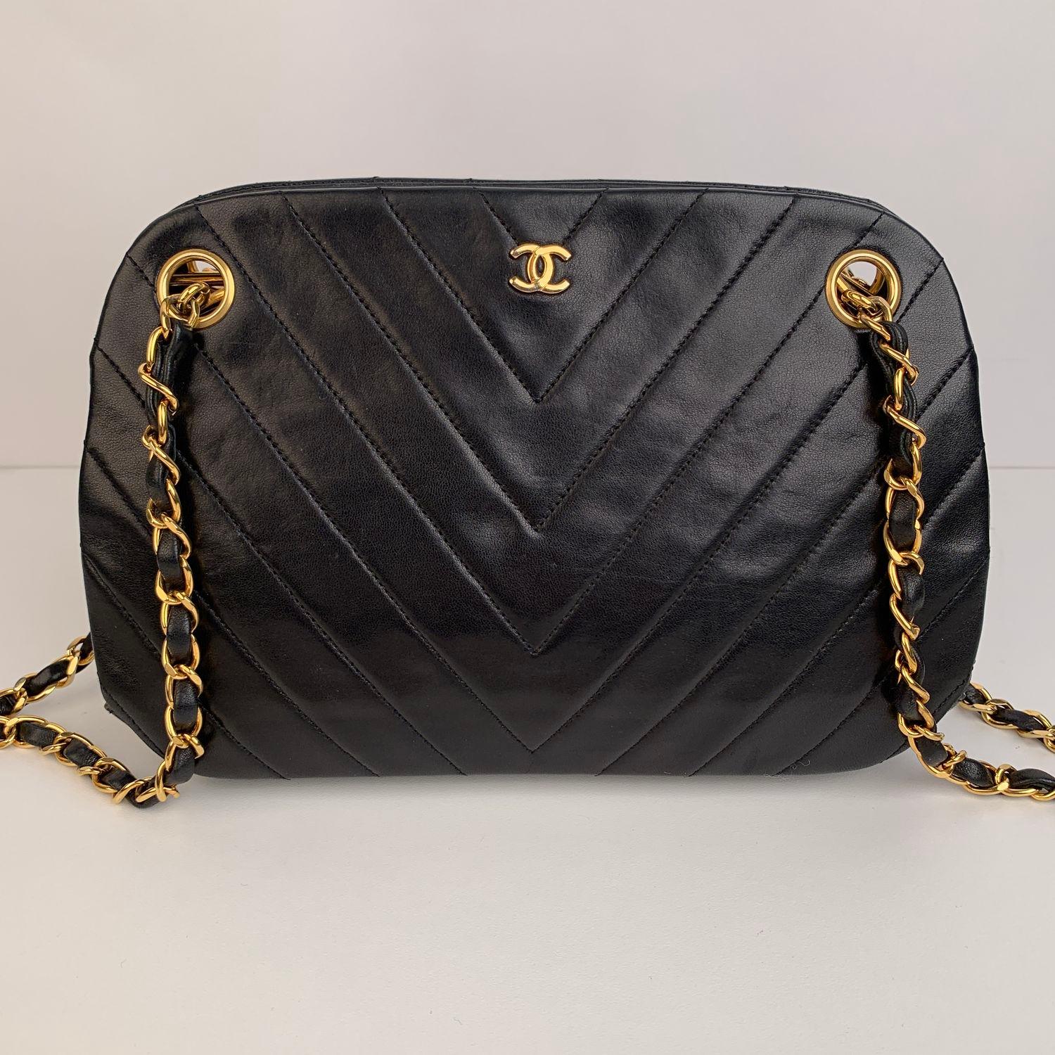Sophisticated black Chevron V-quilted leather shoulder bag by CHANEL with double gold metal chain and interwoven leather shoulder straps. Gold metal CC - CHANEL logo on the front. The bag has a main compartment (with kiss lock closure) with other 2