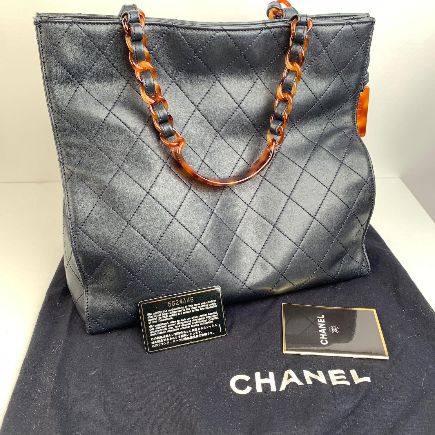 CHANEL Vintage Shopping Tote in Navy Blue quilted leather,  from the 90s. Tortoise chain link top handles threaded with leather. Tortoise lucite Chanel pendant detailing on the side. Double magnetic button closure on top. Fabric interior. 2 side zip