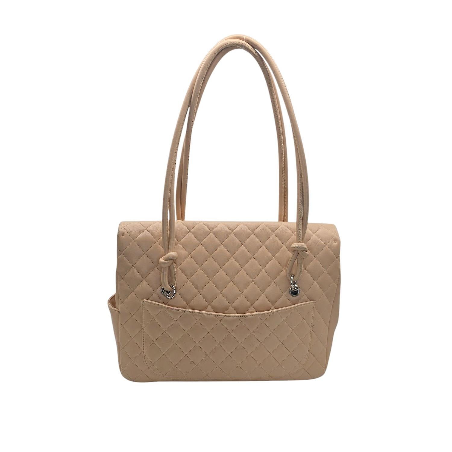 This stylish shoulder bag is crafted of diamond quilted calfskin leather in beige. The bag features tall rolled leather top handles that are knotted at the ends, an off-set black Chanel CC logo patch, and a crossover flap with a silver CC turn lock.