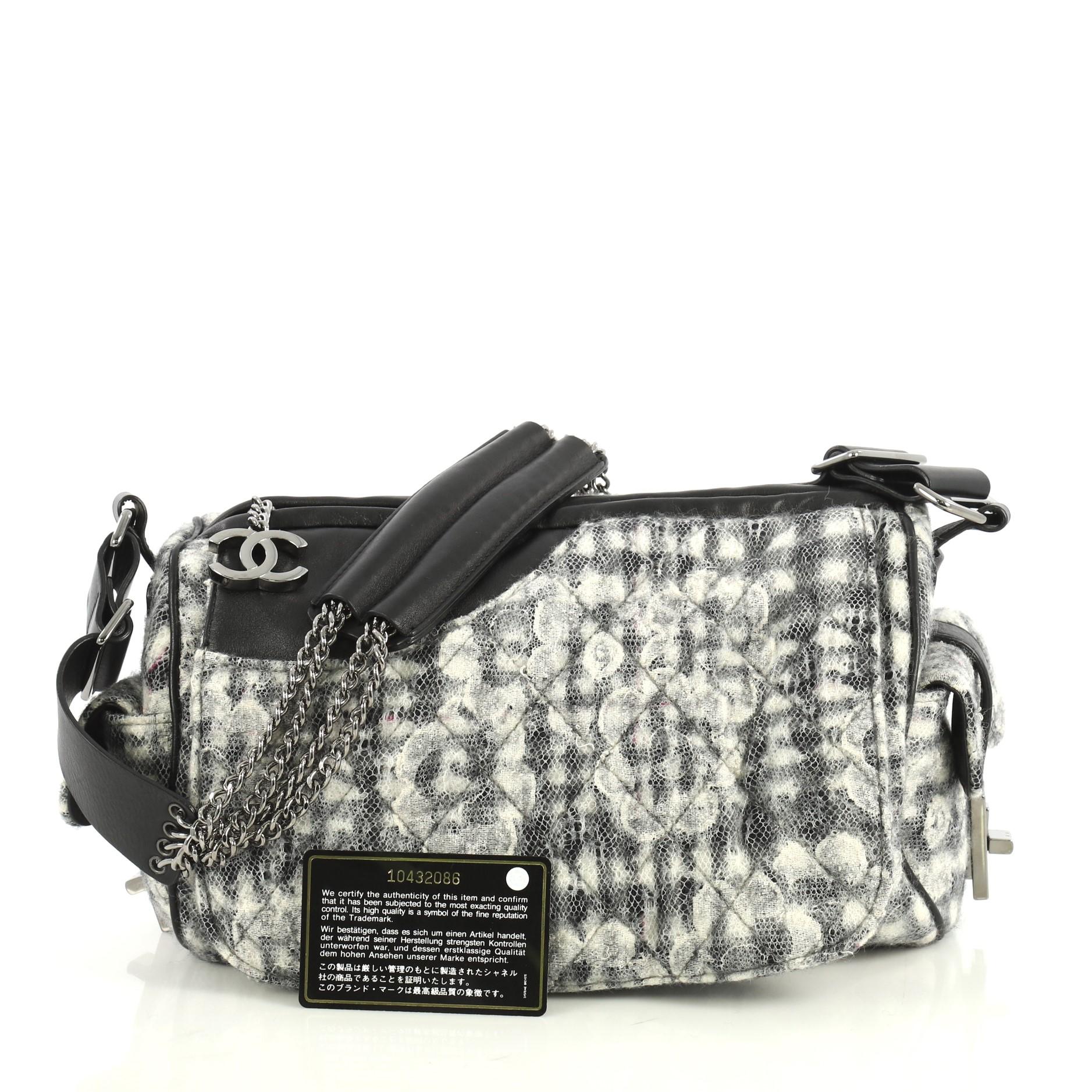 This Chanel Vintage Camellia Flap Camera Bag Quilted Tweed Large, crafted from black, gray and neutral quilted tweed, features triple chain link shoulder straps with black leather pads, exterior side pockets with mademoiselle turn-lock closure and