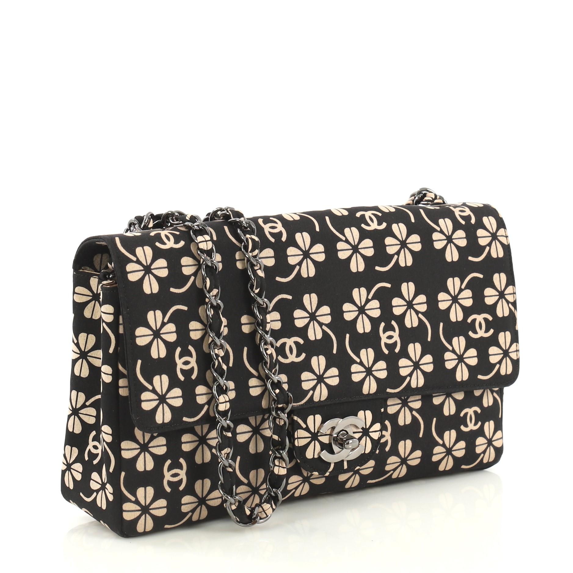 This Chanel Vintage CC Chain Flap Bag Printed Canvas Medium, crafted in black printed canvas, features a woven in canvas chain link strap and gunmetal-tone hardware. Its CC turn-lock closure opens to a beige satin interior with zip and slip pockets.