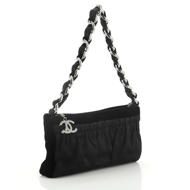 This Chanel Vintage CC Chain Pochette Pleated Satin with Velvet Small, crafted from black pleated satin with velvet, features woven-in chain link handle and gunmetal-tone hardware. Its zip closure opens to a black fabric interior. Hologram sticker