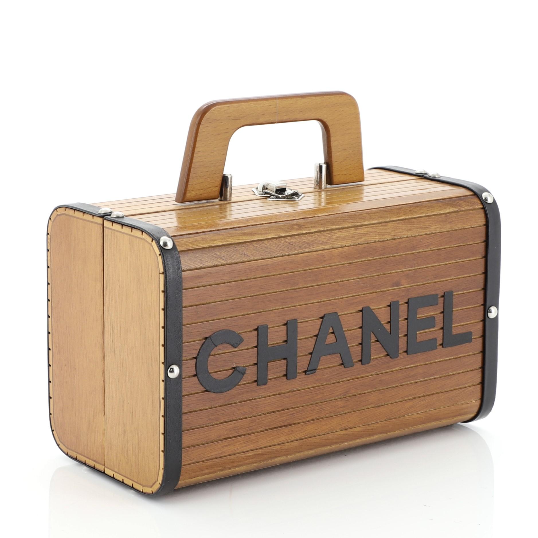 This Chanel Vintage CC Logo Trunk Case Wood, crafted from brown wood, features a top handle and silver-tone hardware. Its clasp closure opens to a red leather interior with zip pocket. Hologram sticker reads: 3987259. 


Condition: Excellent. Scuffs