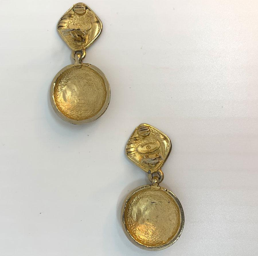 The clips come from Maison CHANEL. In gilded metal with gold leaf, each one hangs a padded round with a CC engraved in its center.
The clips are vintage and in good condition. With a length of 6.3 centimeters, for a width (the round CC) of 3