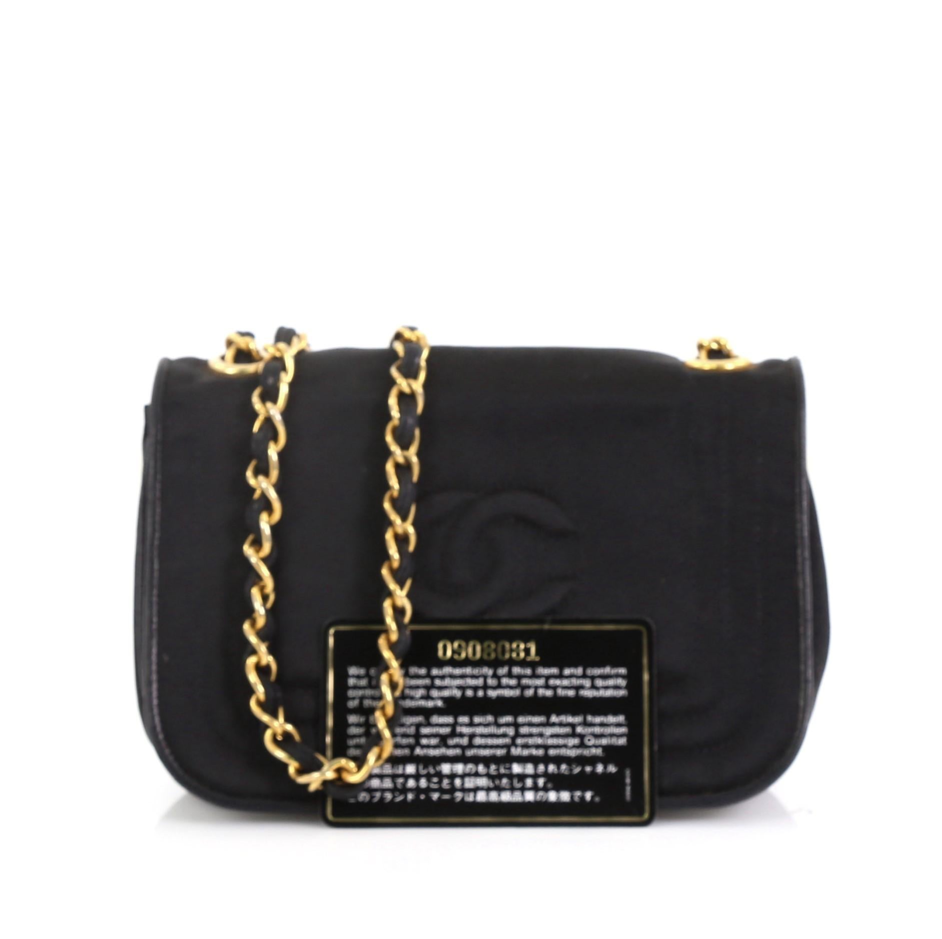 This Chanel Vintage CC Stitch Flap Bag Satin Mini, crafted from black satin, features woven-in leather chain strap, CC stitched logo, and gold-tone hardware. Its hidden magnetic snap closure opens to a red leather interior with zip pocket. Hologram