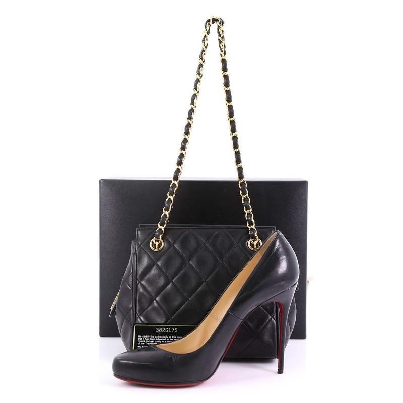 This Chanel Vintage Chain Tote Quilted Lambskin Mini, crafted from black quilted lambskin, features dual woven-in leather chain straps and gold-tone hardware. Its zip closure opens to a black leather interior with slip pocket. Hologram sticker
