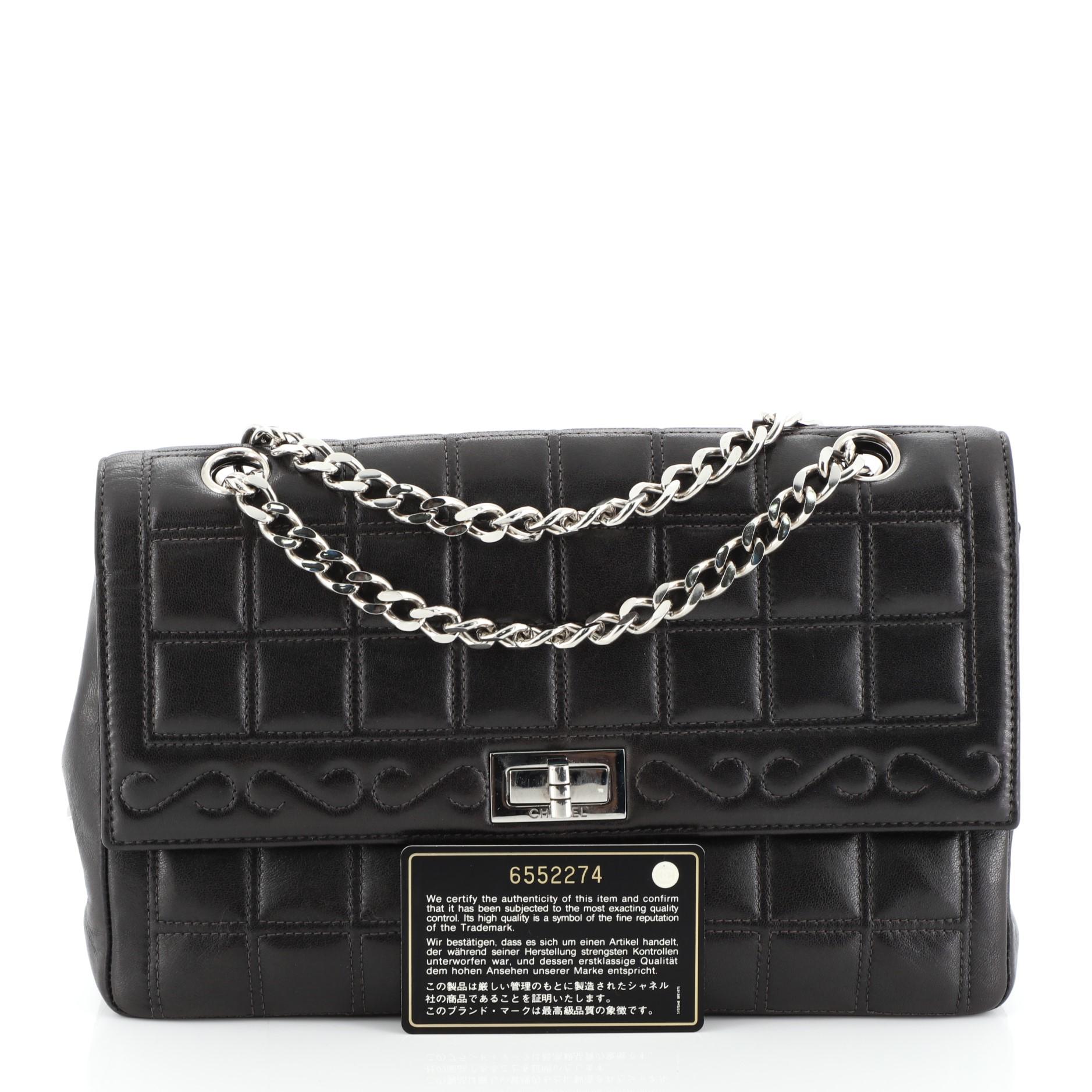 This Chanel Vintage Chocolate Bar Mademoiselle Chain Flap Bag Quilted Leather Medium, crafted from black quilted leather, features woven in leather chain link straps and silver-tone hardware. Its mademoiselle turn-lock closure opens to a black