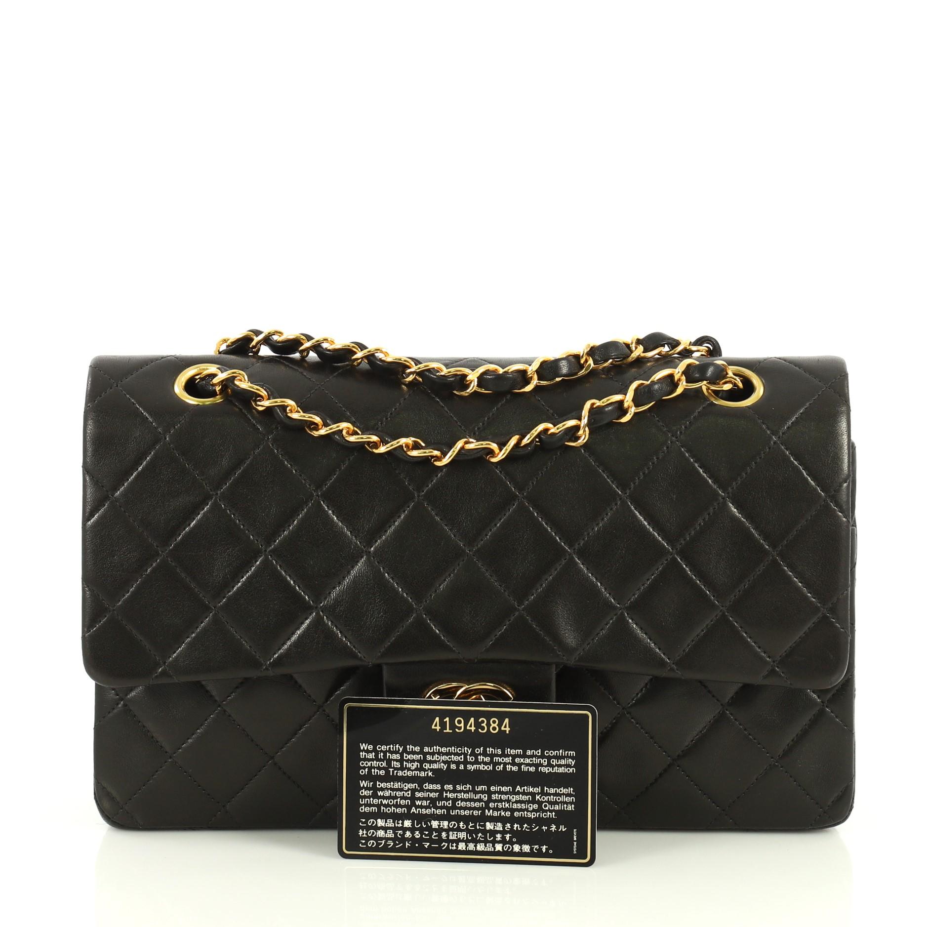 This Chanel Vintage Classic Double Flap Bag Quilted Lambskin Medium, crafted from black quilted lambskin leather, features woven-in leather chain strap, exterior back slip pocket and gold-tone hardware. Its frontal CC turn-lock closure opens to a