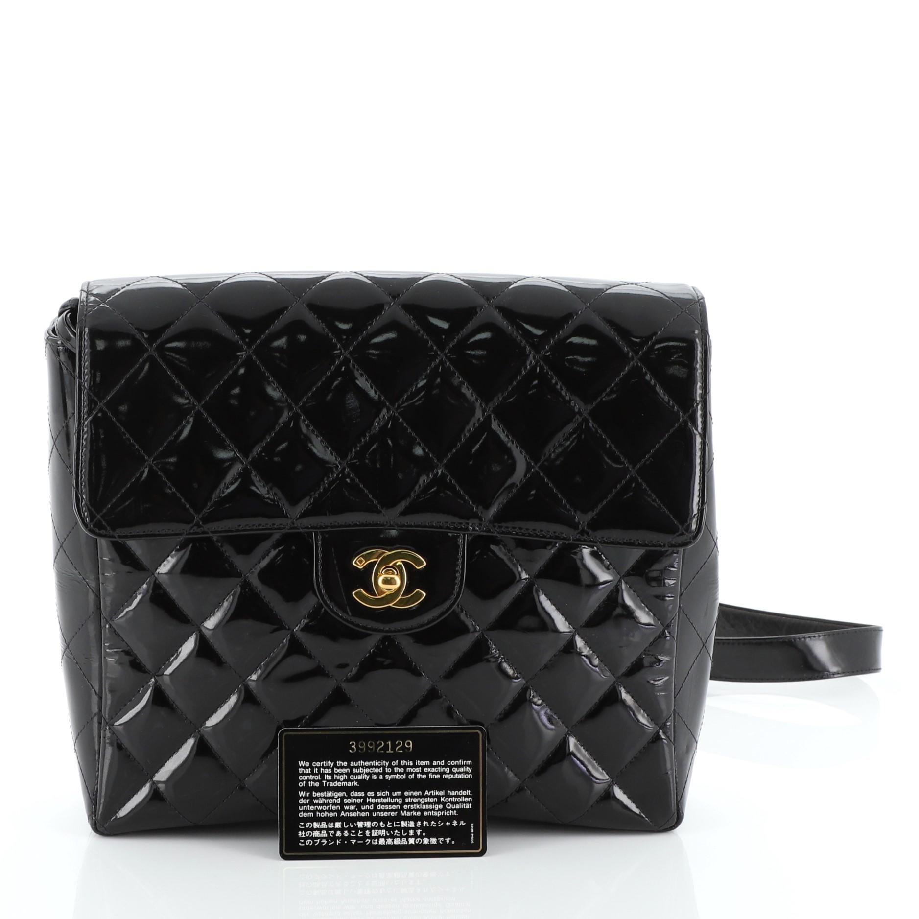 This Chanel Vintage Classic Flap Backpack Quilted Patent Medium, crafted from black quilted patent leather, features dual flat leather straps with woven-in leather chains and gold-tone hardware. Its CC turn-lock closure opens to a black leather
