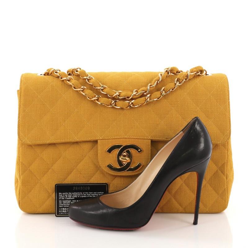 This Chanel Vintage Classic Single Flap Bag Quilted Coated Canvas Maxi, crafted from yellow quilted coated canvas, features an exterior back pocket, woven-in coated canvas chain strap, and gold-tone hardware. Its CC signature turn-lock closure opens