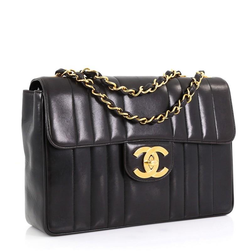This Chanel Vintage Classic Single Flap Bag Vertical Quilt Lambskin Jumbo, crafted in black vertical quilted lambskin, features woven-in leather chain link strap and gold-tone hardware. Its CC turn-lock closure opens to a burgundy leather interior