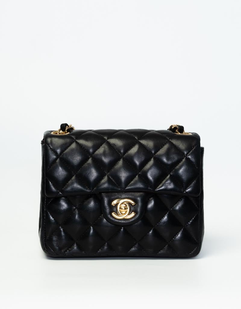 This vintage Mini Square Flap Bag features an exterior of black diamond quilted lambskin leather, gold toned hardware, a front flap with a signature interlocking CC turn lock clasp closure, and a gold toned chain interlaced with leather. The