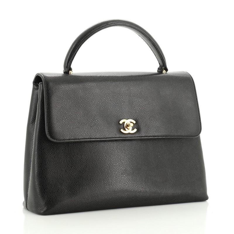 This Chanel Vintage Classic Top Handle Flap Bag Caviar Jumbo, crafted in black caviar leather, features a single looped top handle, exterior slip pocket, and gold-tone hardware. Its CC turn-lock closure opens to a black leather interior with zip and