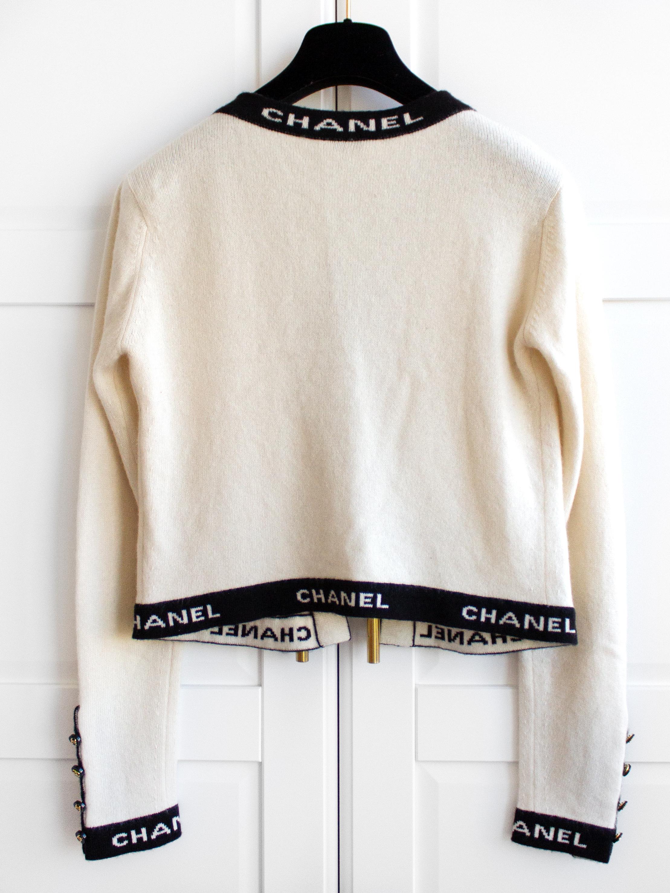 An iconic open-front cashmere cardigan from the 1995 Chanel Cruise Collection. Crafted in Coco Chanel's favorite contrasting colors of ivory white and black, this collector's item is adorned with the CHANEL logo on the edges and signature CC