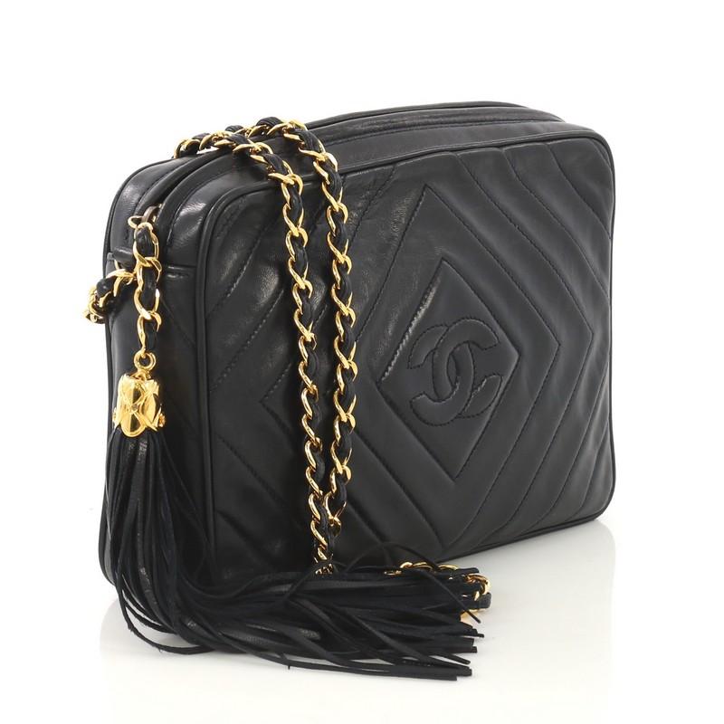 This Chanel Vintage Diamond CC Camera Bag Quilted Leather Medium, crafted from navy blue quilted leather, features woven in leather chain strap, side tassels, and gold-tone hardware. Its top zip closure opens to a navy blue leather interior with zip