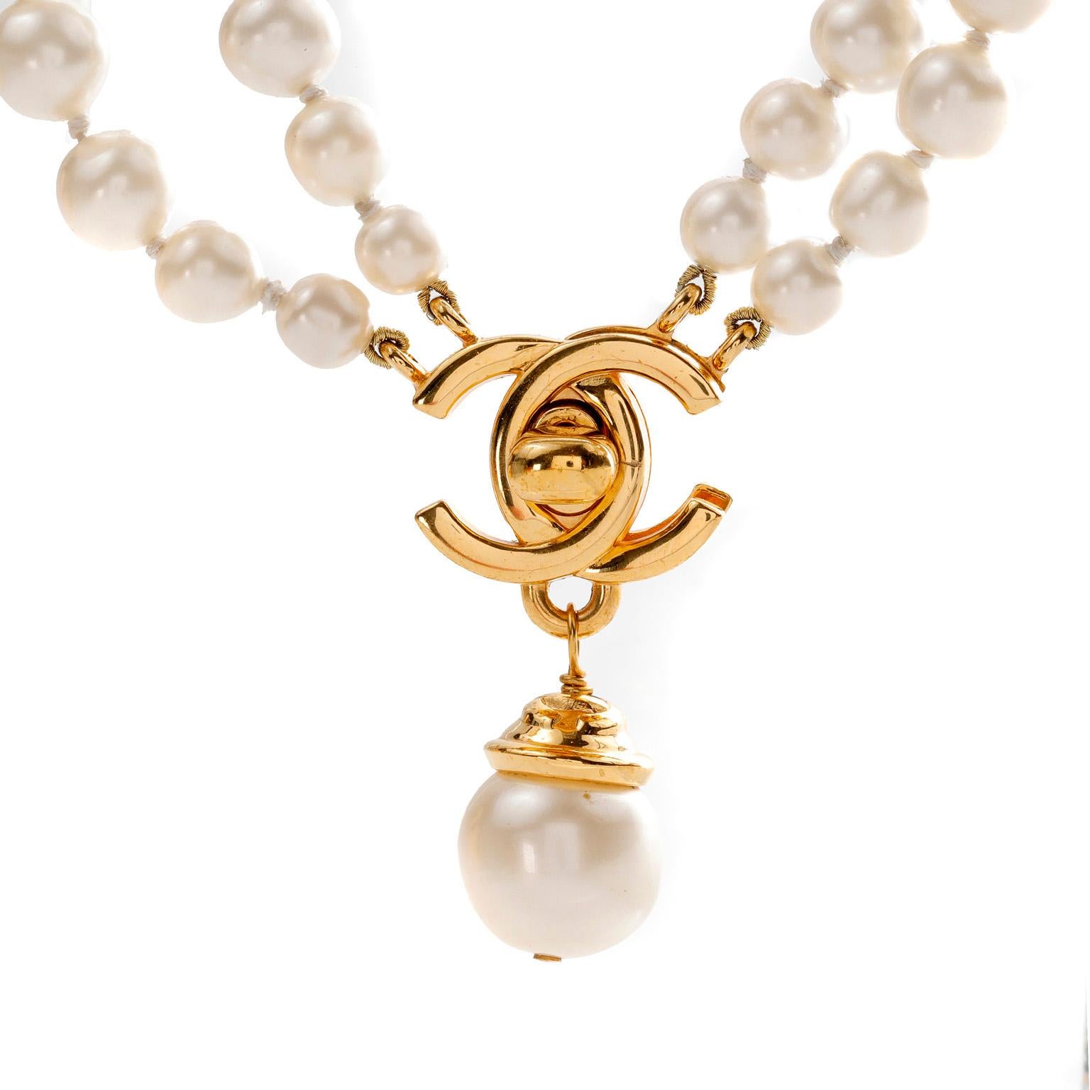 This authentic Chanel Double Pearl Strand CC Lock Necklace is in exquisite vintage condition.  A double strand of faux pearls is anchored by an interlocking CC twist lock in 24 karat gold plated metal.  A single faux pearl dangles from the CC lock. 