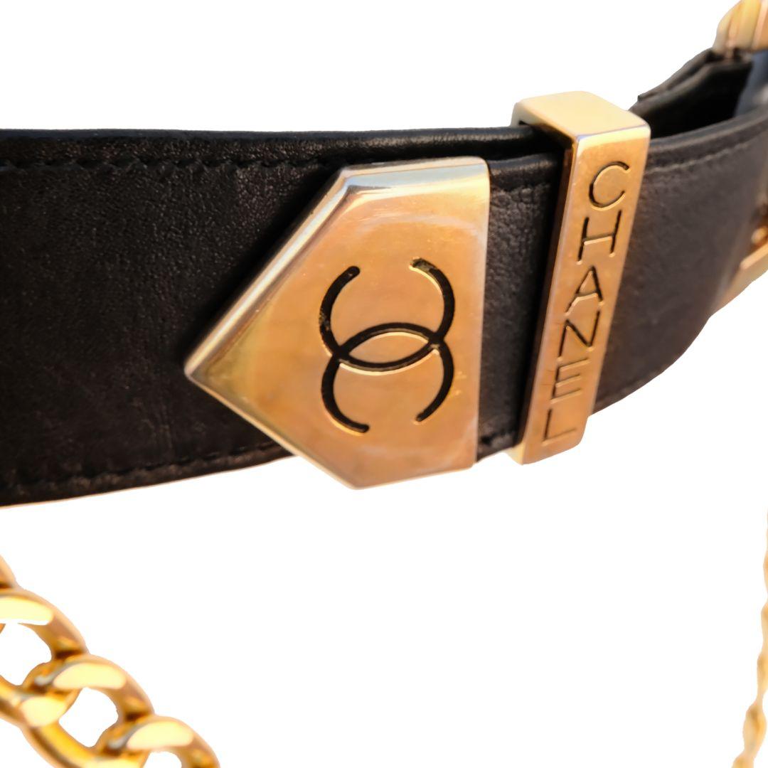 Vintage Chanel black leather belt featuring a gold plated chain with CC logo.

Rue Cambon Paris medallion coin detail attaches chain to the side hook.

Interlocking CC logo stamped on the angled metal of the belt end.

Chanel embossed on the belt
