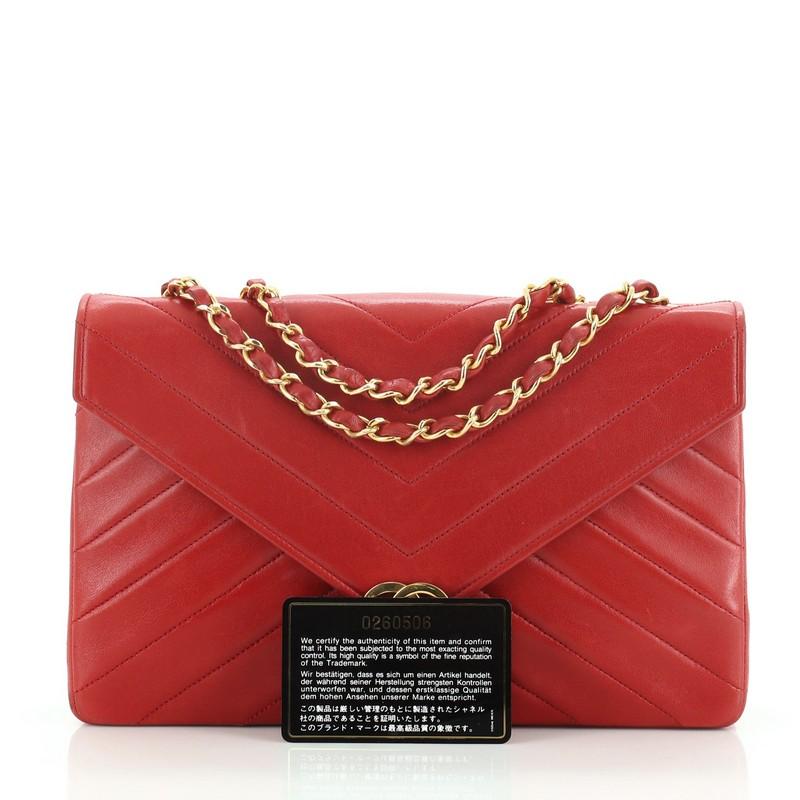 This Chanel Vintage Envelope Flap Bag Chevron Lambskin Medium, crafted from red chevron lambskin leather, features an envelope flap, woven-in leather chain strap and gold-tone hardware. Its CC turn-lock closure opens to a red leather interior with