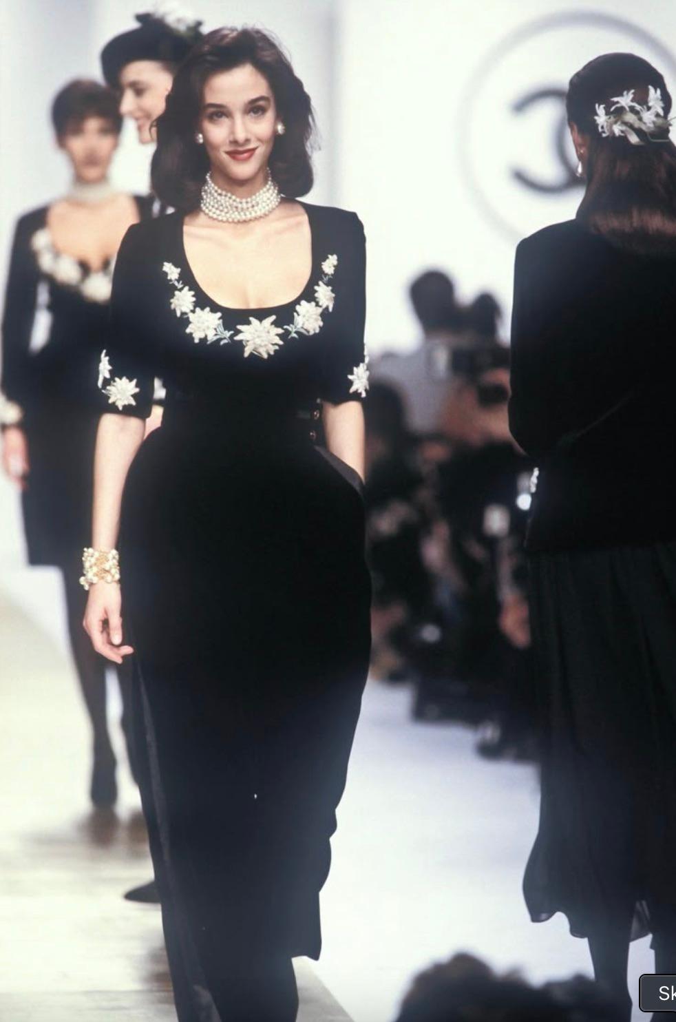 This rare vintage Chanel top is from the Fall/Winter 1988 collection, crafted in rich black velvet and meticulously adorned with plush, hand-embroidered edelweiss blooms. The floral embellishments, featuring soft ivory chenille petals and delicate