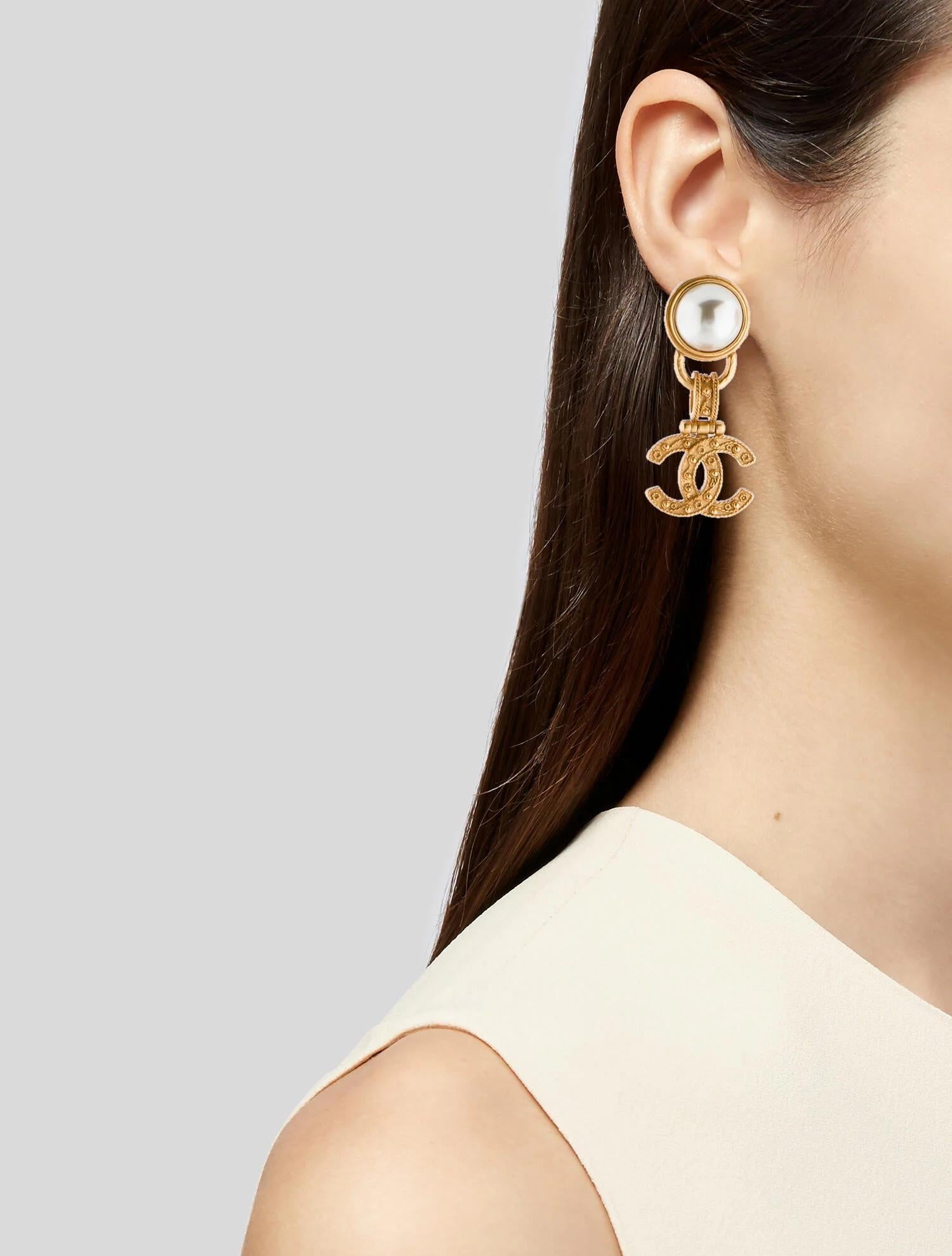 These vintage earrings are from the spring 1994 collection and are made with gold tone metal and a faux pearl. The earrings feature clip closure, designer signature, designer code and a highly polished and textured finish with a drop of about 2.2