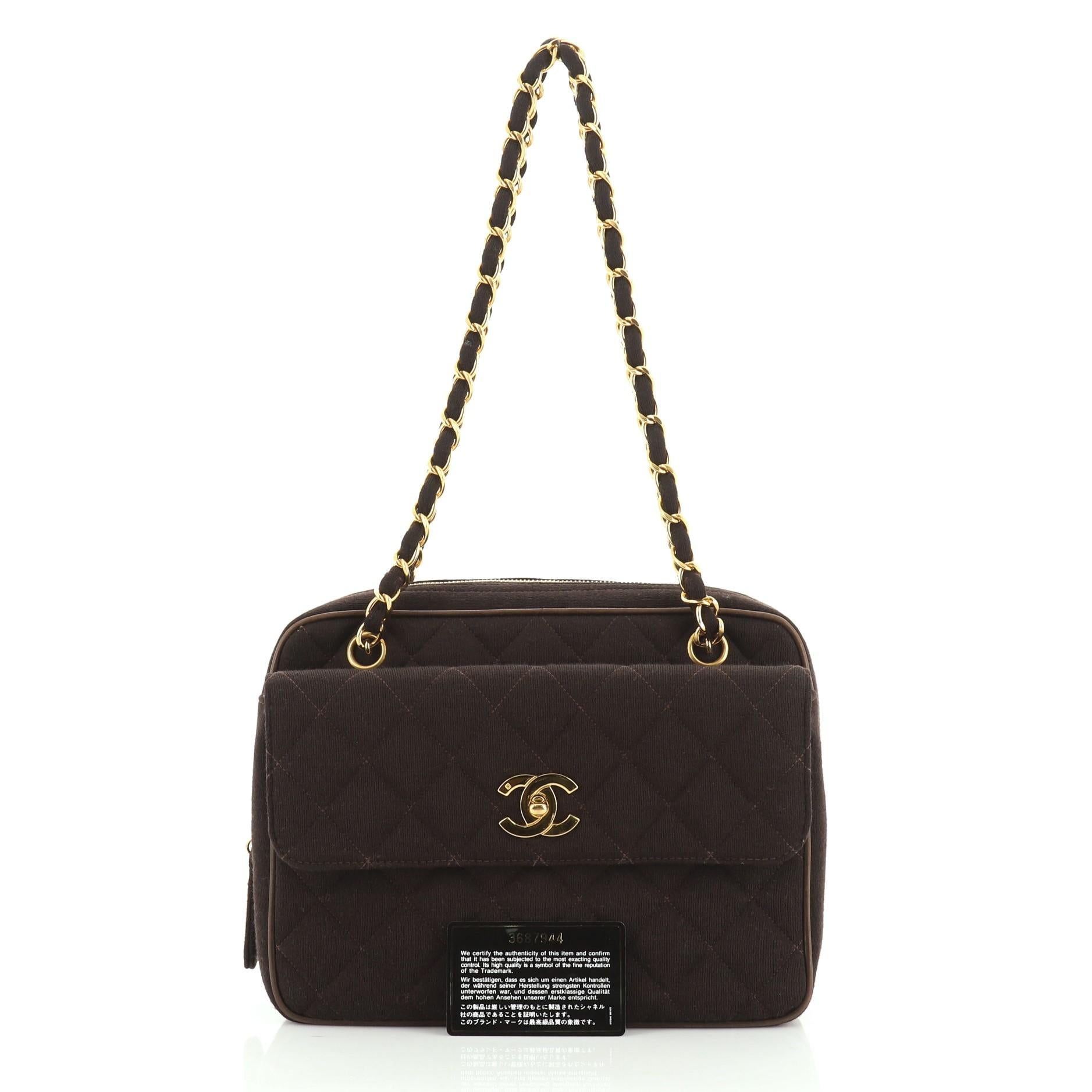 This Chanel Vintage Front Pocket Camera Bag Quilted Jersey Medium, crafted in brown quilted jersey, features woven-in jersey chain straps, front flap pocket with CC turn- lock closure, and gold-tone hardware. Its zip closure opens to a brown leather