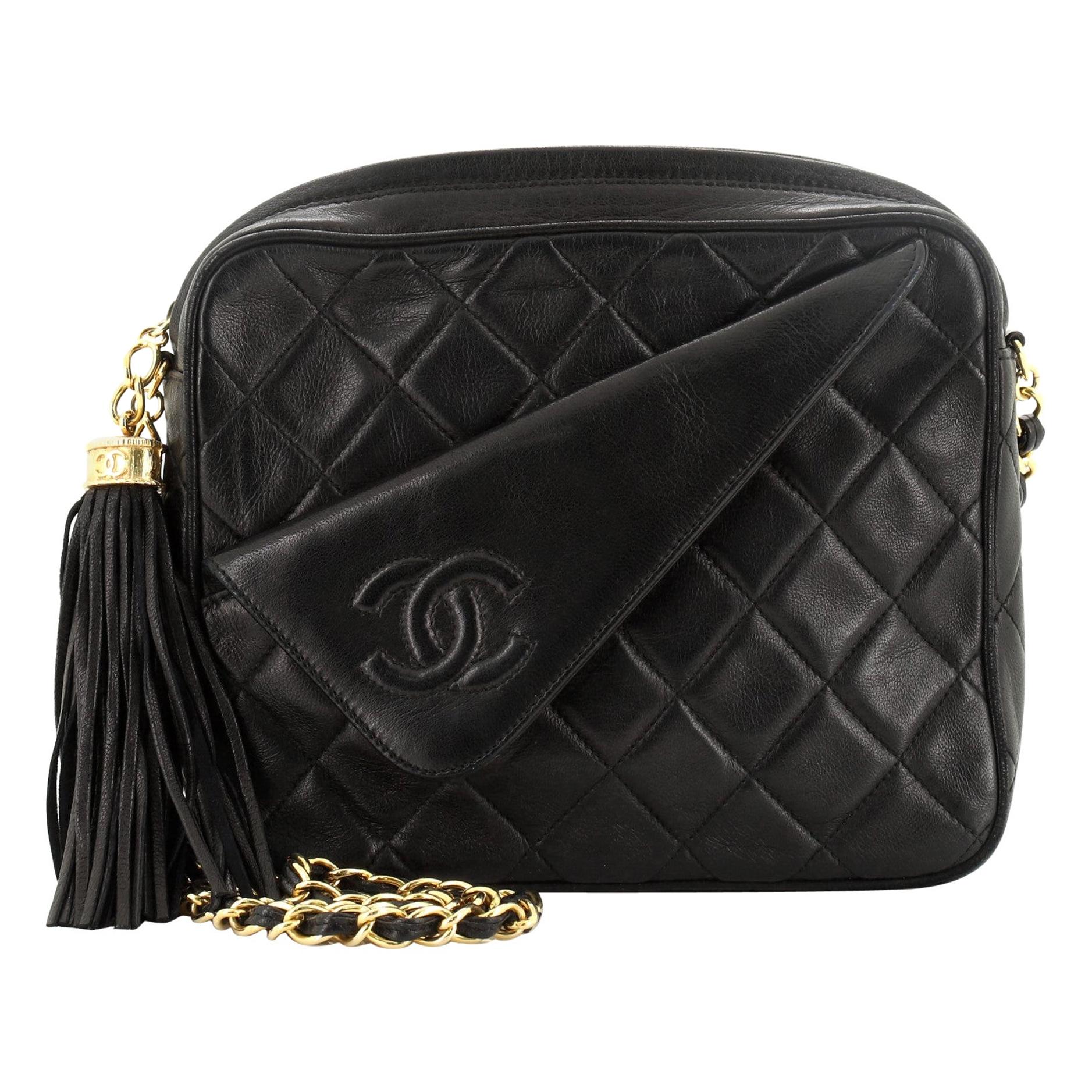 This Chanel Vintage Front Pocket Camera Bag Quilted Lambskin Small, crafted in black quilted leather, features a chain link strap, front flap pocket with CC stitched logo, and gold-tone hardware. Its top zip CC charm tassel closure opens to a black
