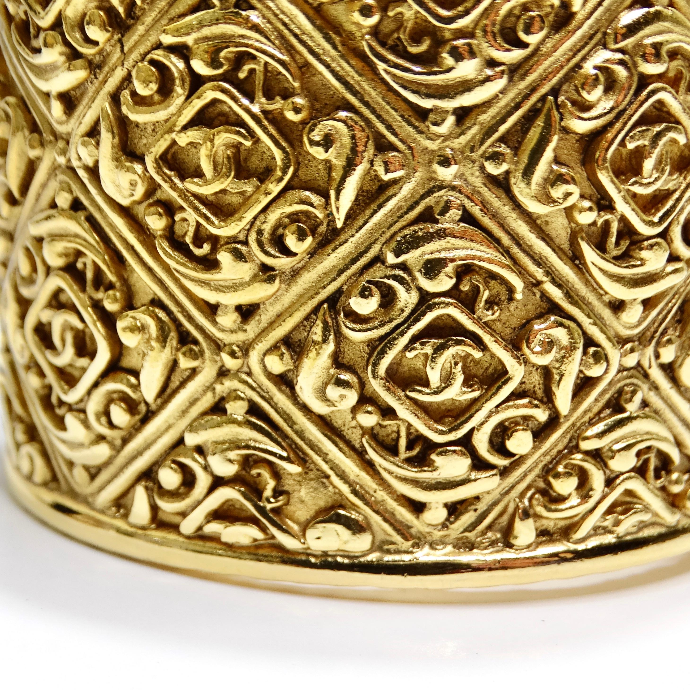 Zeitlose Eleganz mit dem Chanel Vintage Gold Tone CC Hinged Bangle Bracelet. Dieses atemberaubende Stück ist perfekt verarbeitet und zeichnet sich durch ein klobiges Design mit komplizierten geometrischen Ätzungen aus, die Luxus und Raffinesse