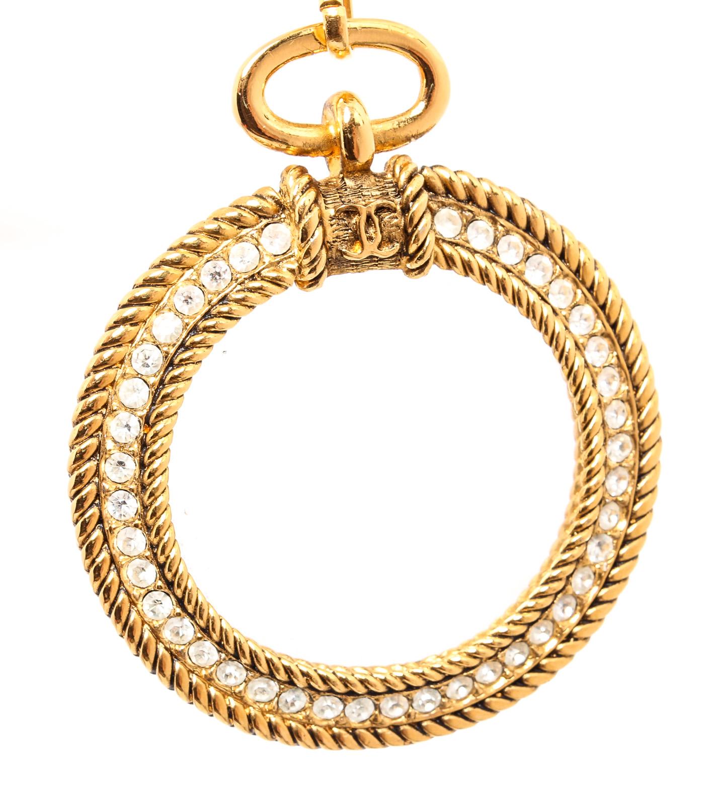 Gold-tone chain link with faux pearl and rhinestone details and magnifying CC glass pendant and a large spring clasp closure.

24134MSC