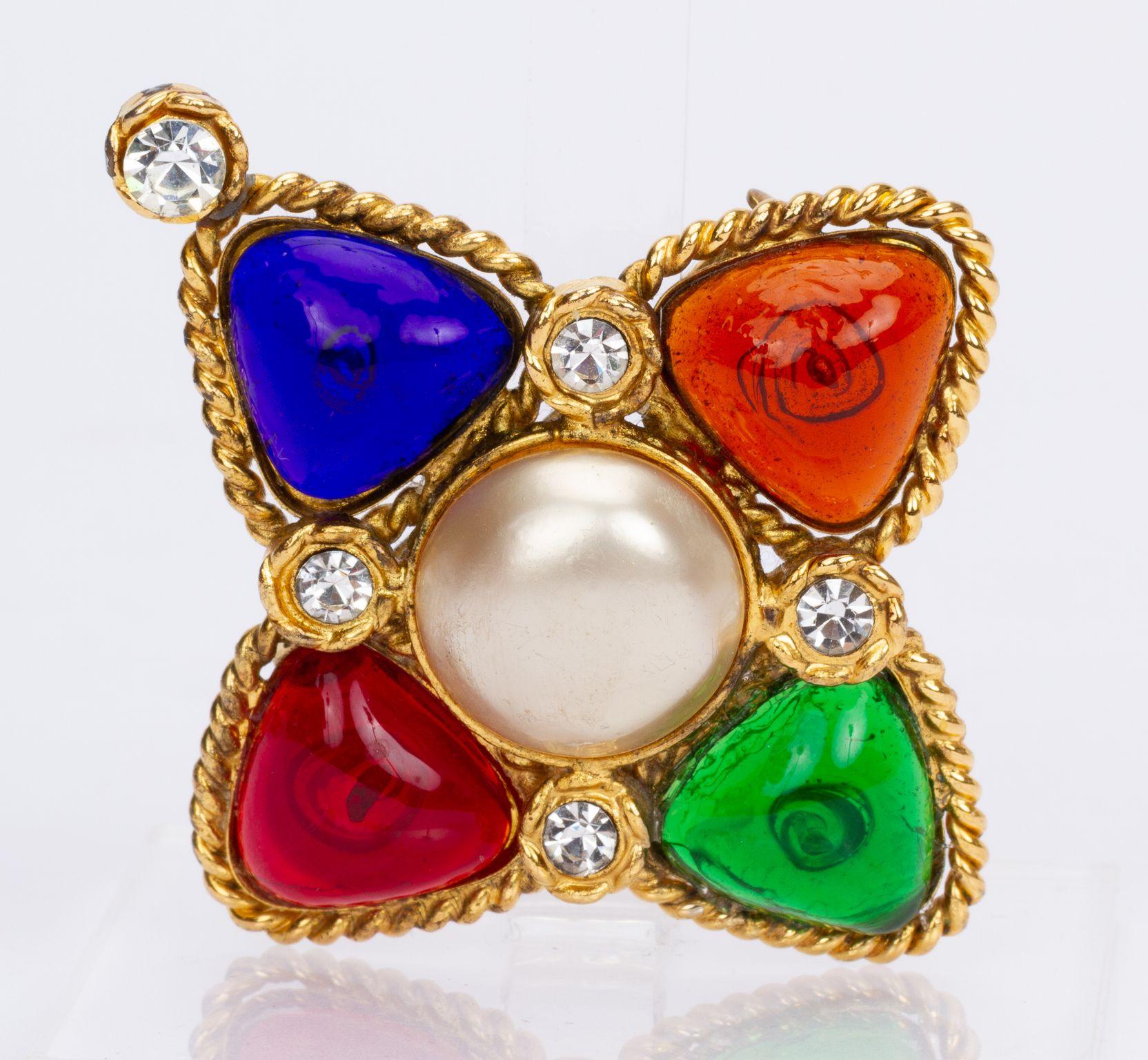 Chanel vintage brooch in gold with multicolored stones. As well as four crystals surrounding one stone in the middle. At the back of the brooch is a cc logo. The piece is in very good condition, with a small soldering in the back and comes with the