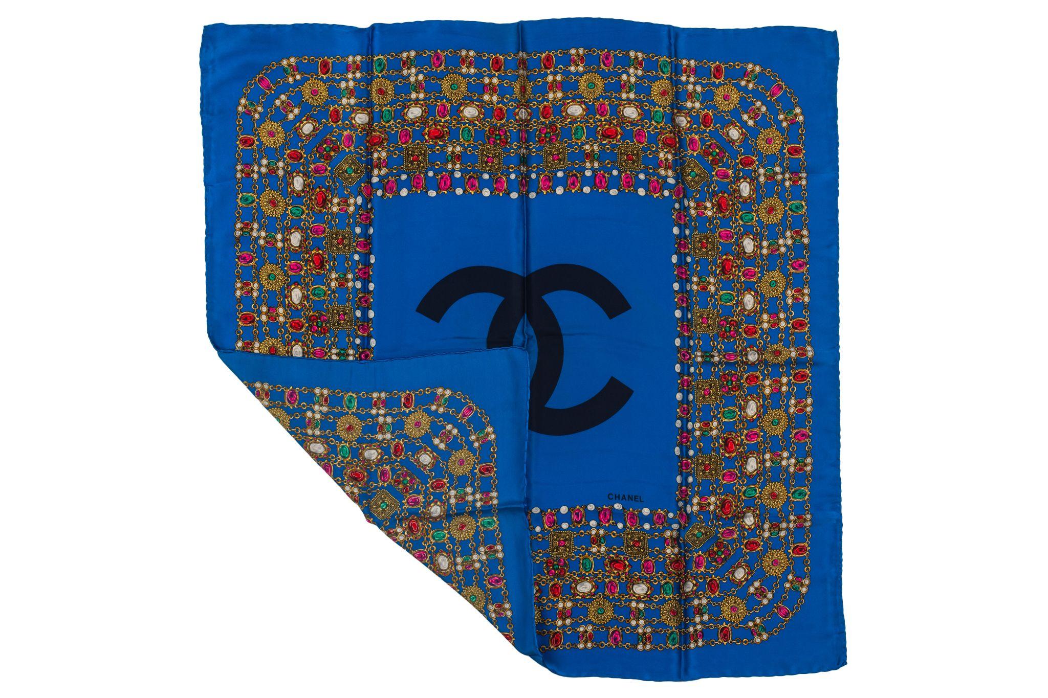 Chanel Shawl in a vibrant blue with a CC logo in the middle surrounded by a pattern of different gripoix jewelry stones. Piece is in excellent condition.