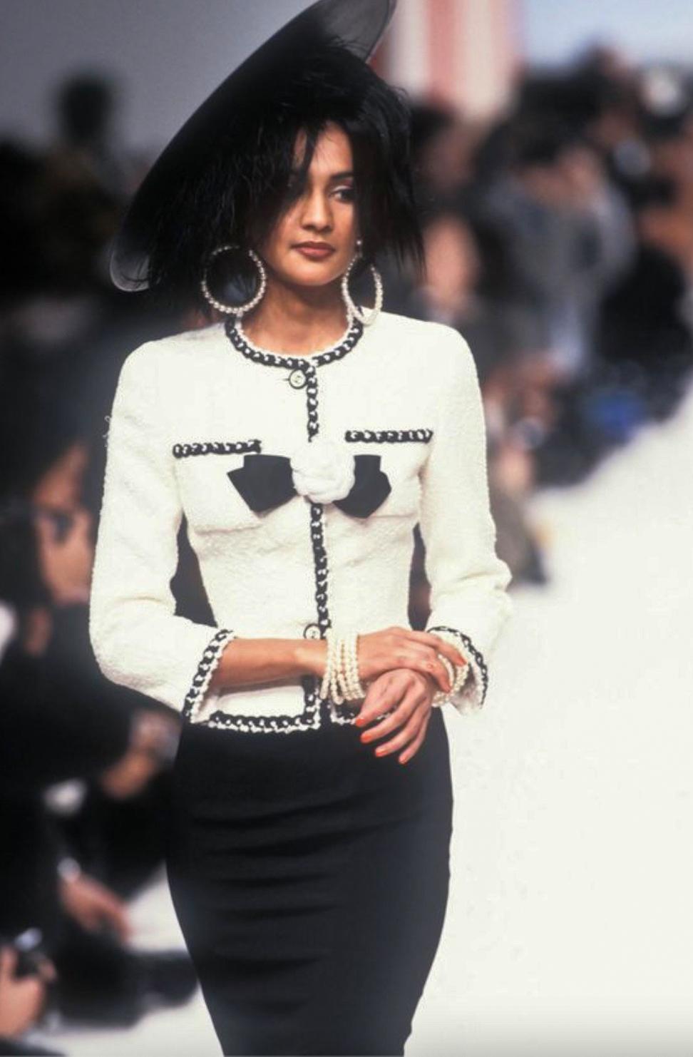 Indulge in the sophistication of Chanel's Haute Couture Spring/Summer 1995 collection with this exceptional tweed jacket. This classic collarless jacket in off-white tweed is accentuated by contrasting black braided trims, two chic patch pockets,