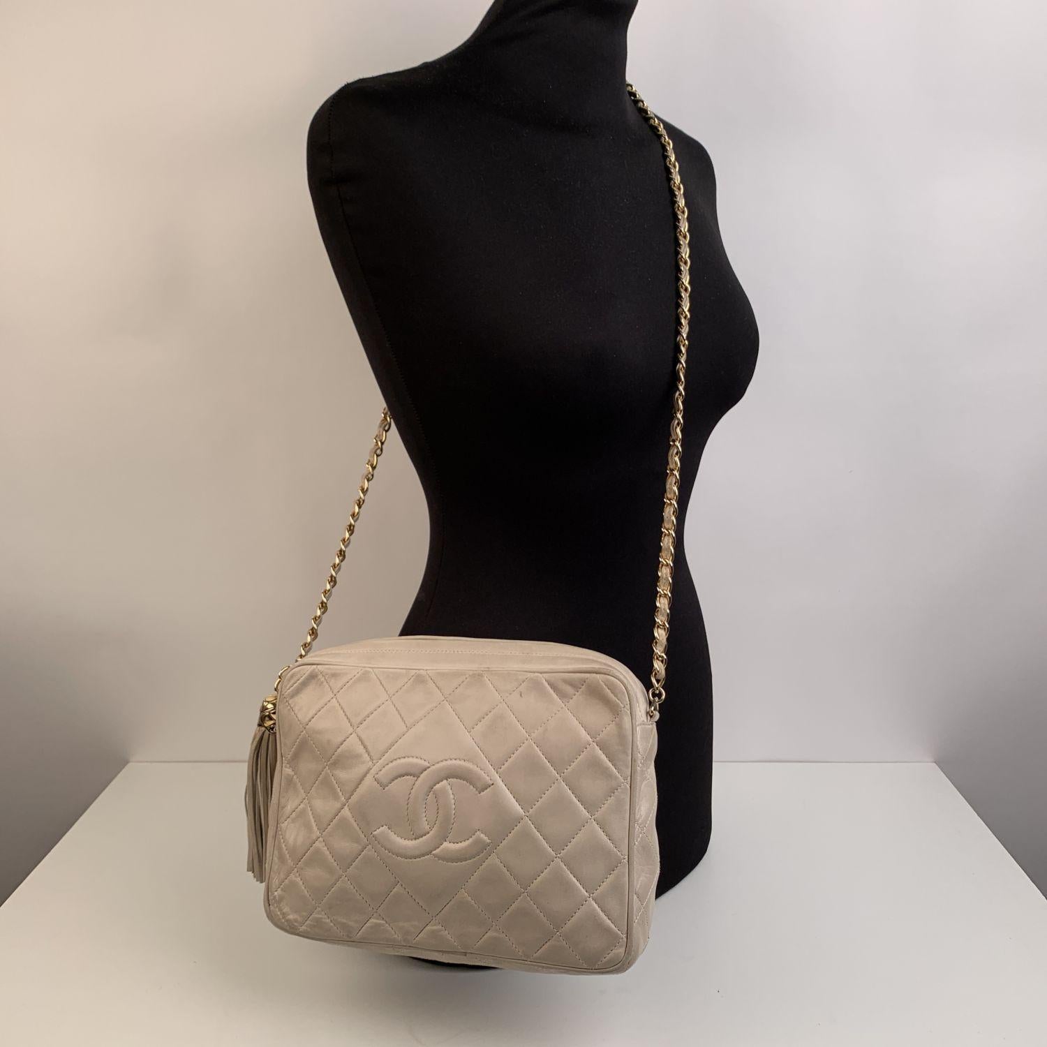 Vintage Chanel Classic Camera bag with CC - CHANEL logo front stitching . Period/Era: 1990s. Ivory quilted lambskin leather. Upper zip closure. Chanel iconic interwoven chain. Tassel zipper pull . Lined in beige lambskin. 1 side zip pocket inside.