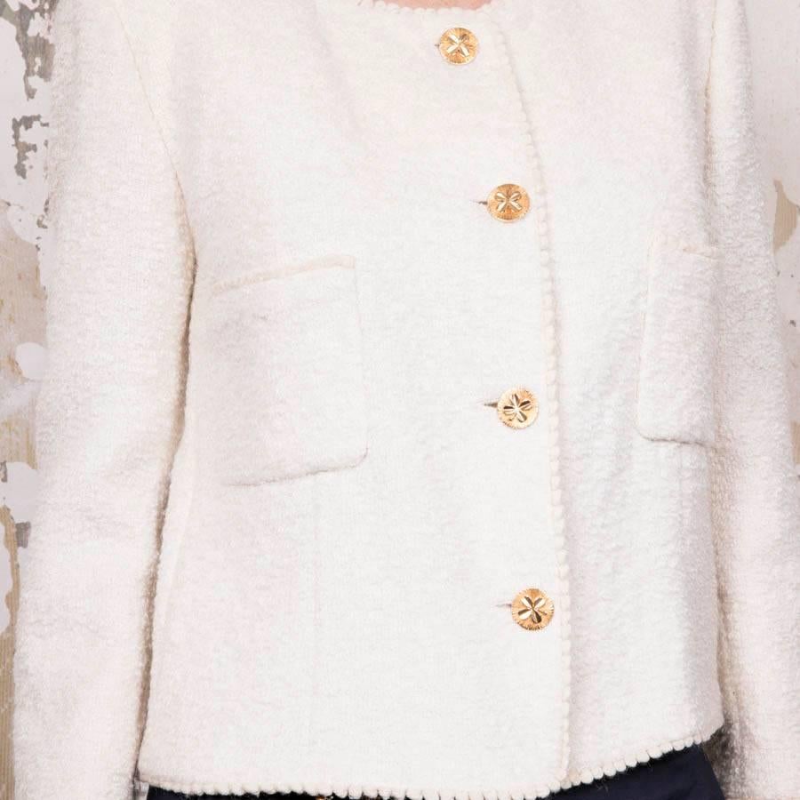 Chanel vintage ecru tweed jacket.  It closes with four golden metal buttons. We find the same button at each wrist and two slit pockets at the waist. 
Good used condition despite a slight discoloration of the silk under the armpits and small