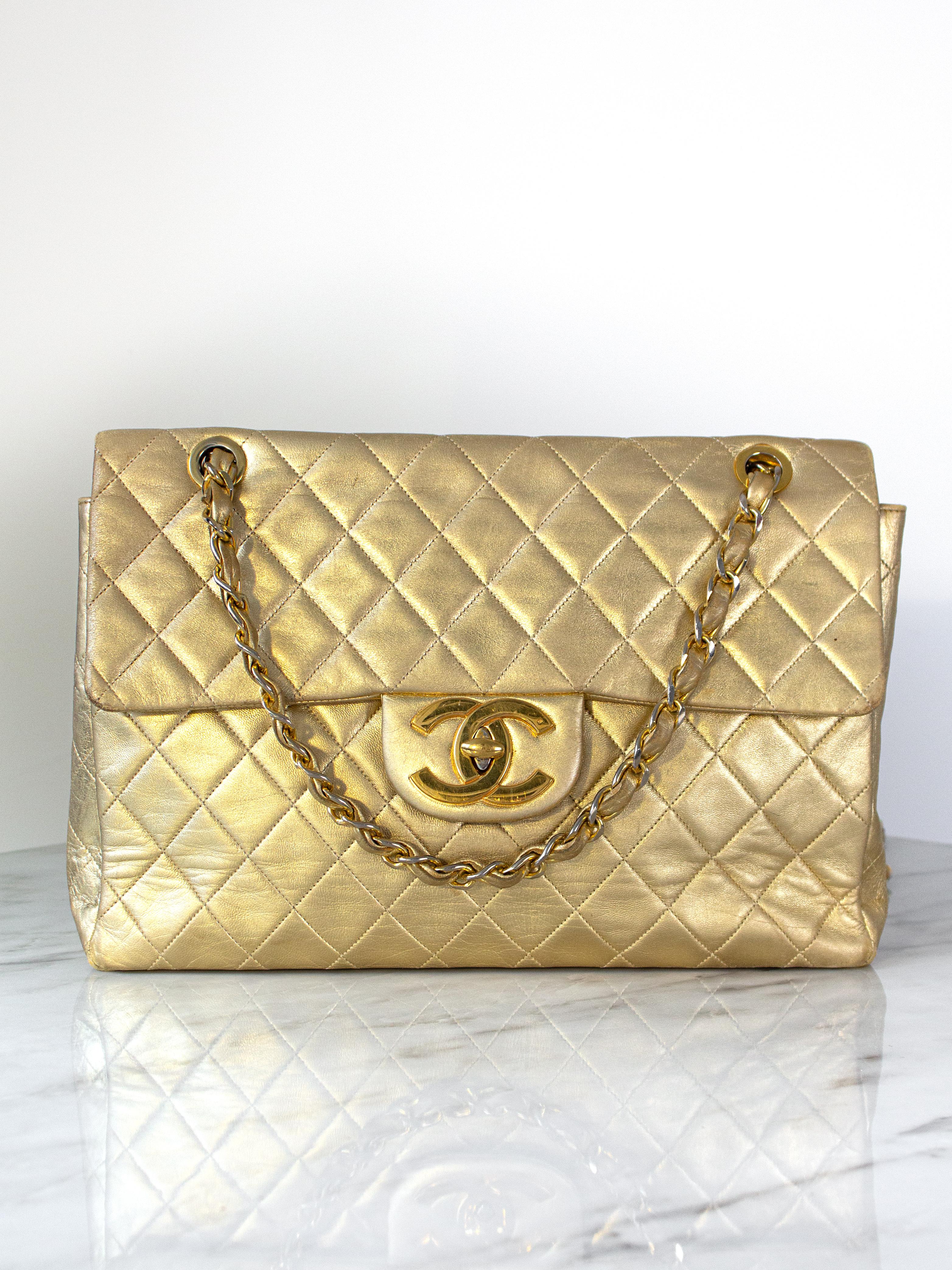 Chanel Jumbo XL Maxi bag in a stunning metallic gold shade, a rare find originating from the 1990s. Crafted from luxurious quilted lambskin leather in a radiant gold tone, this piece is adorned with exquisite gold-plated hardware. Secured by a