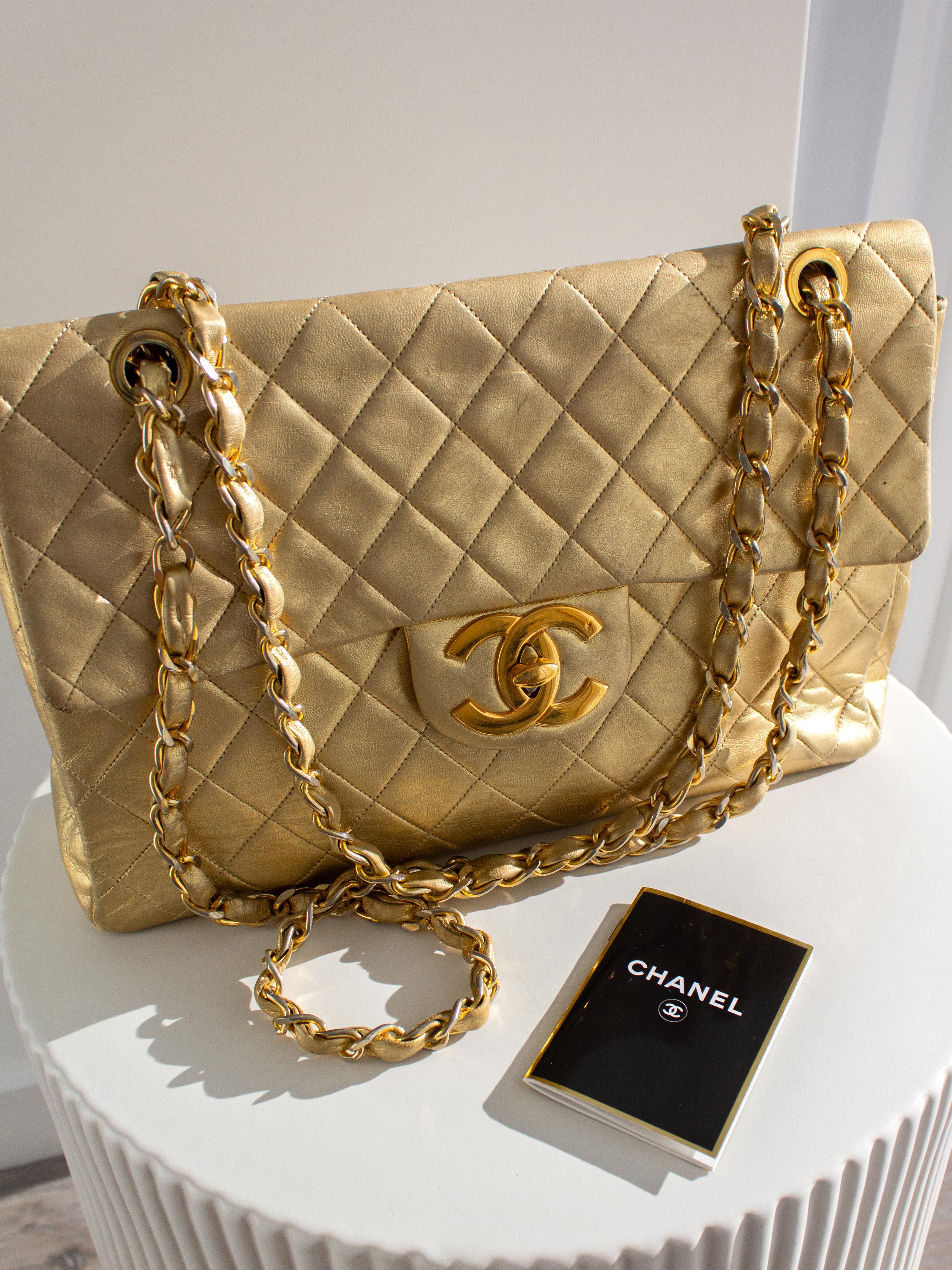 Chanel Jumbo XL Maxi bag in a stunning metallic gold shade, a rare find originating from the 1990s. Crafted from luxurious quilted lambskin leather in a radiant gold tone, this piece is adorned with exquisite gold-plated hardware. Secured by a