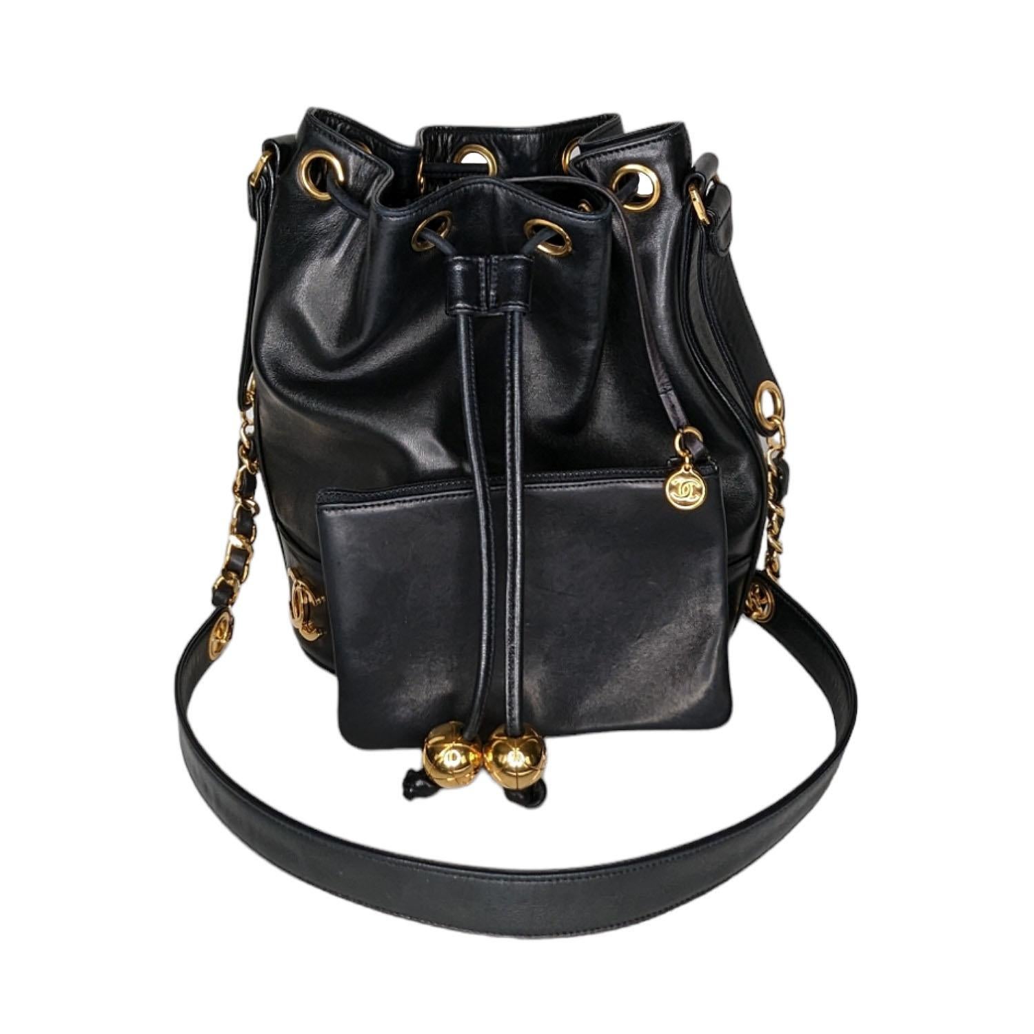 Chanel Vintage Lambskin CC Drawstring Bucket Bag in Black. This stylish bucket-style shoulder bag is crafted of grained calfskin leather. The bag features six CC logos in gold (three in the front and three in the back) and a gold chain link and