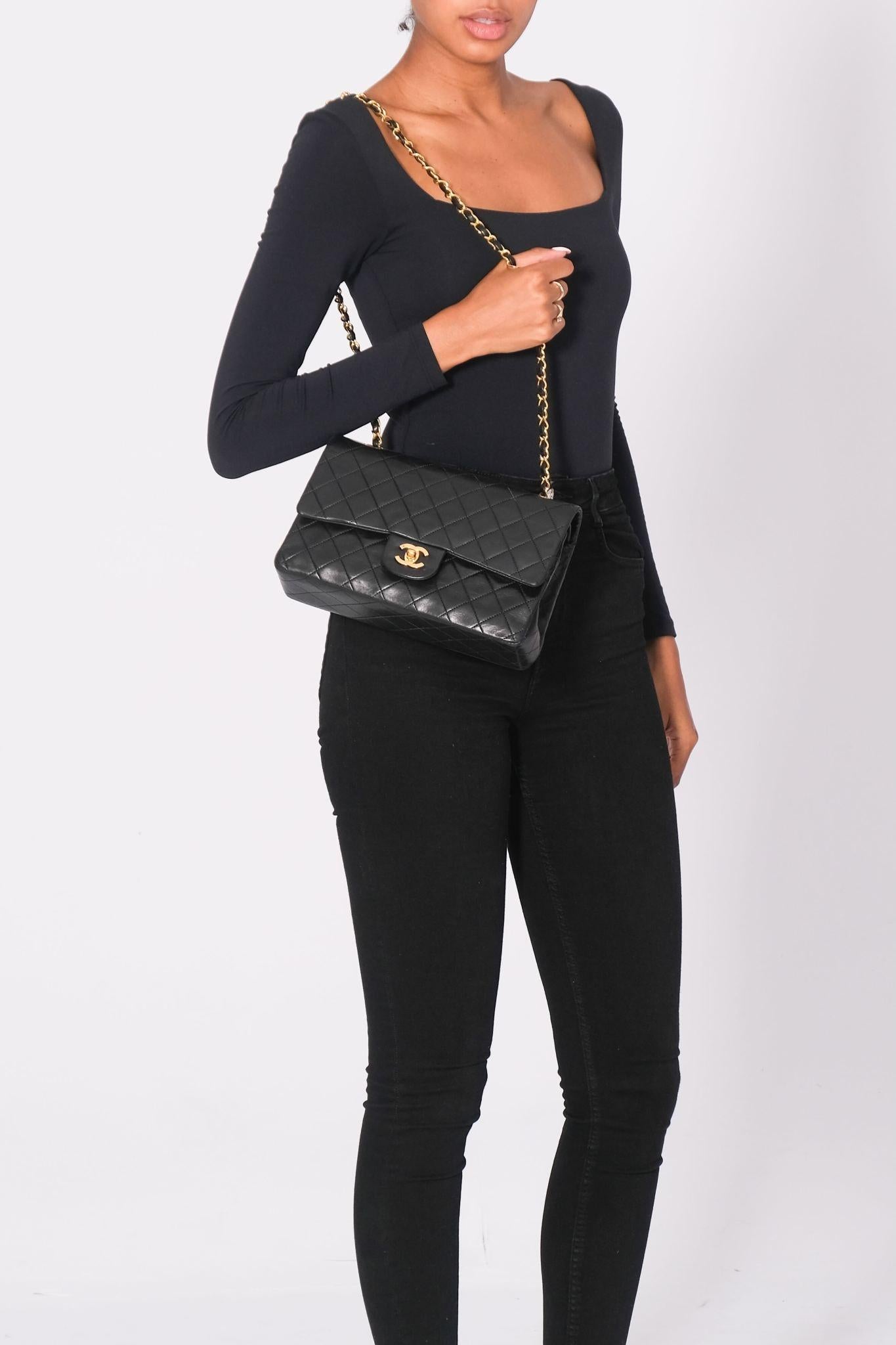 Este bolso bandolera está fabricado en piel de cordero acolchada en rombos de color negro. El bolso tiene un bolsillo plano trasero, una correa para el hombro de eslabón de cadena dorada enhebrada en piel y un cierre giratorio CC dorado a juego en