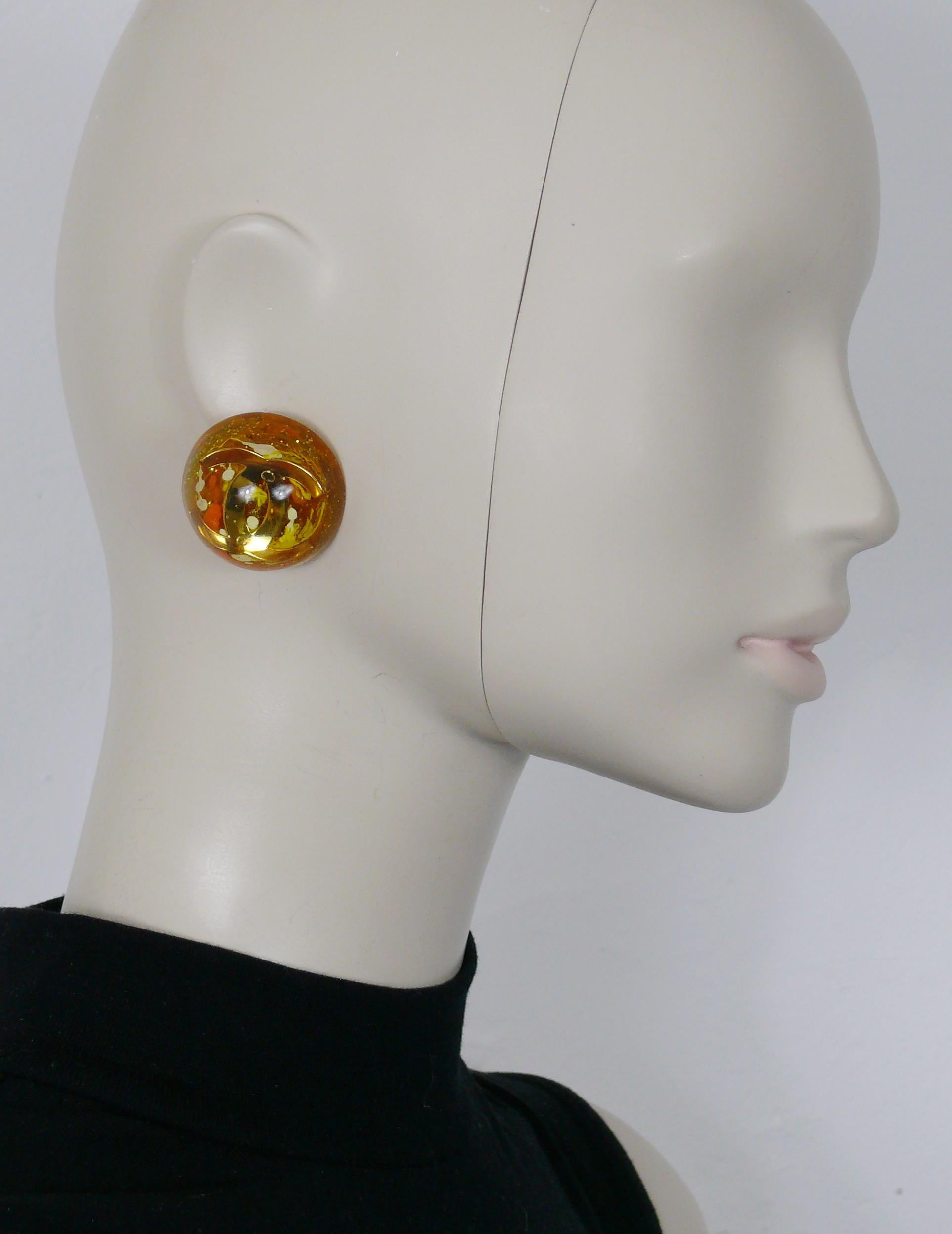 CHANEL vintage 1993 massive domed resin clip-on earrings embellished with a large gold toned CC logo inlaid at the center, glitter sequins and color splash inlaids.

Collection n°28 (year : 1993).
Jewelry creative director : VICTOIRE DE