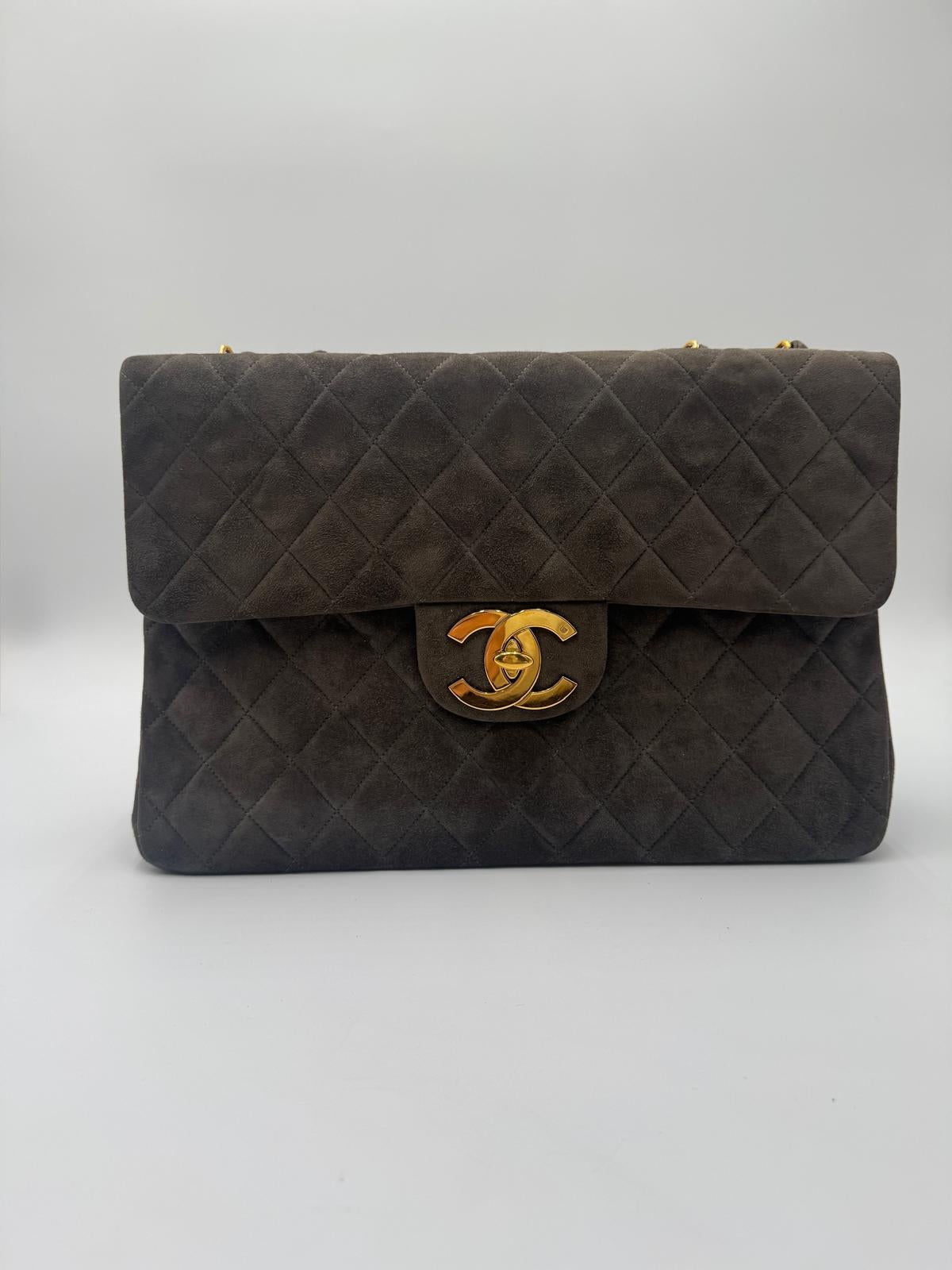 This Chanel vintage maxi flap comes in a rich dark suede with 24k gold-plated hardware. It’s in excellent condition, with only a small smudge on the bottom of the bag (please refer to photos). The structure is strong, and the suede remains plush and