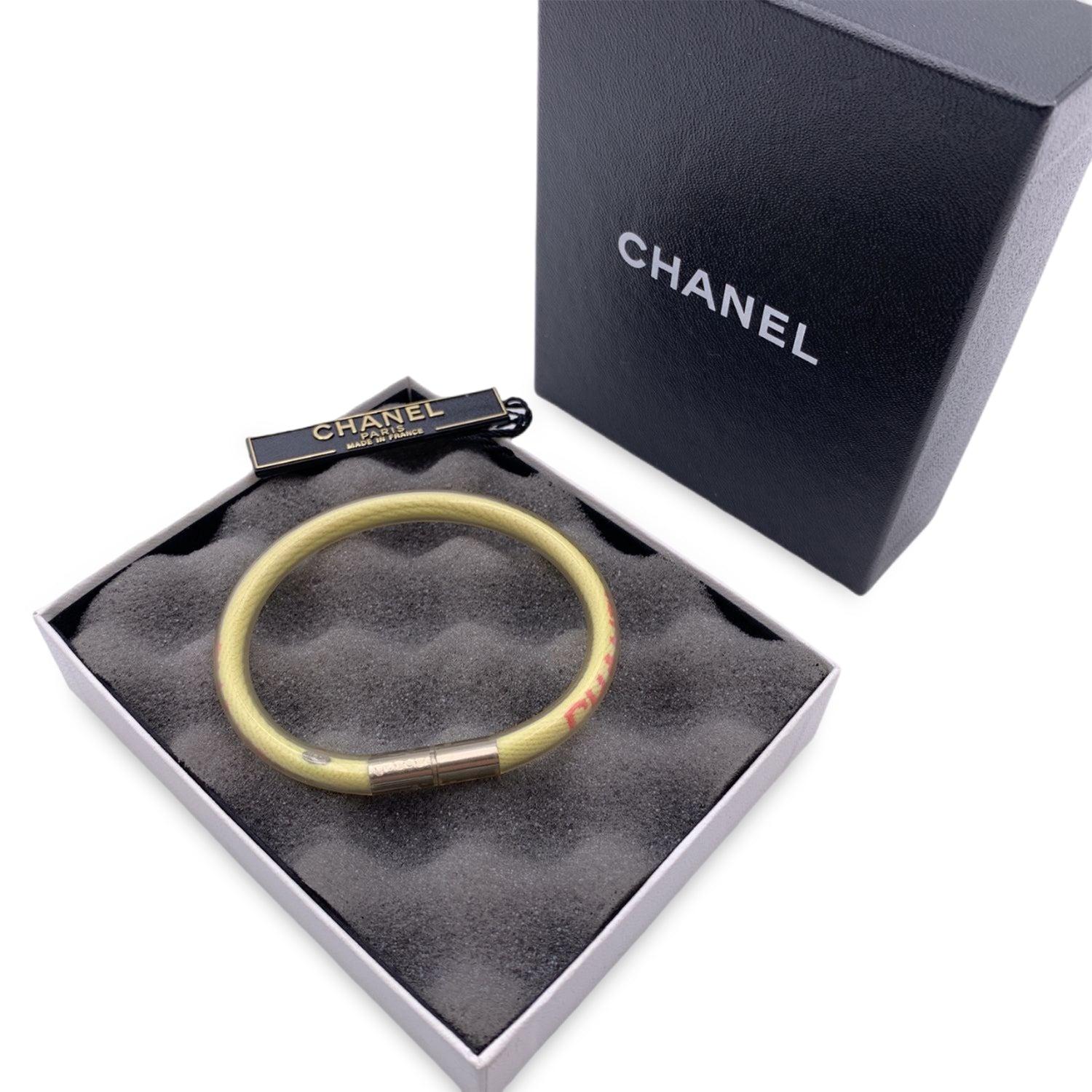 Lovely bracelet by CHANEL, crafted of pale yellow woven and clear vinyl tube. Pink CHANEL signature. Secured with a silver tone twist lock. 'Chanel 00 CC T Made in France' oval hallmark near the closure. Internal circumference: 6.5 inches - 16.5 cm