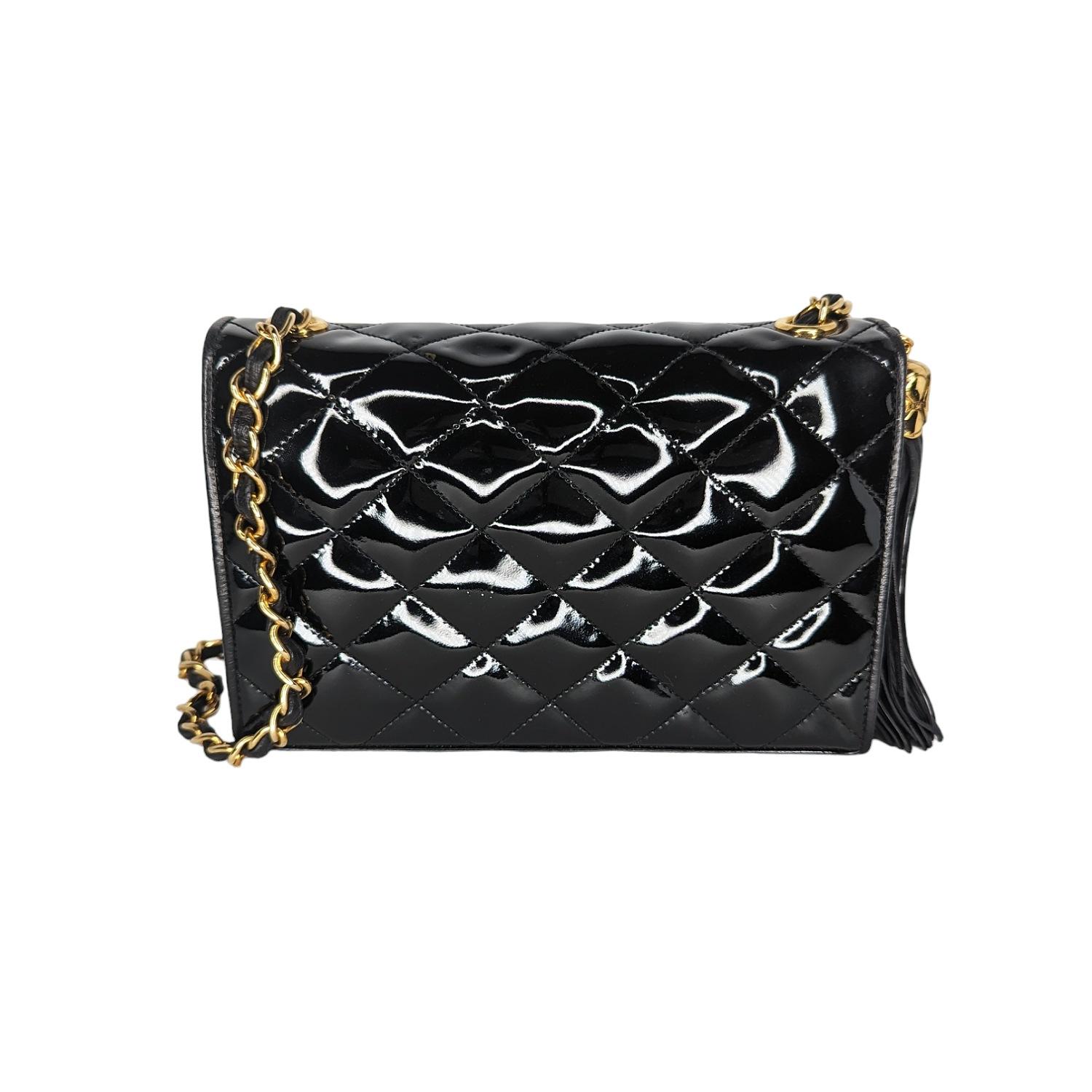 Chanel Vintage Patent Quilted CC Tassel Flap Bag in black. Featuring an interlocking CC logo at front face, 24K plated gold-tone hardware, leather threaded chain link shoulder strap, tassel accent, single interior pocket, leather lining and flap