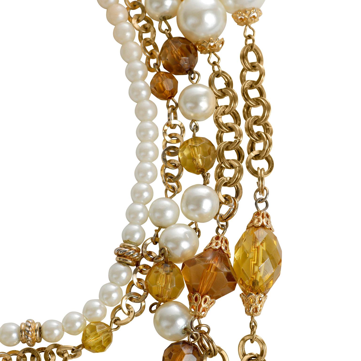 This authentic Chanel Pearl and Amber Crystal Layered Bib Necklace is in excellent vintage condition.  Five strands of varied gold chain, amber crystal beads and faux pearls are layered together in this stunning collectible piece.  Anchored all