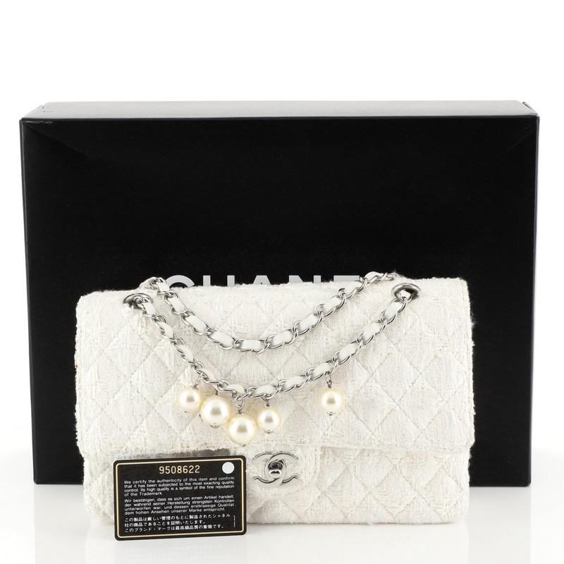 This Chanel Vintage Pearl Chain Classic Double Flap Bag Quilted Tweed Medium, crafted from white quilted tweed, features woven-in leather chain strap with pearls, exterior back pocket, and silver-tone hardware. Its double flap with CC turn-lock