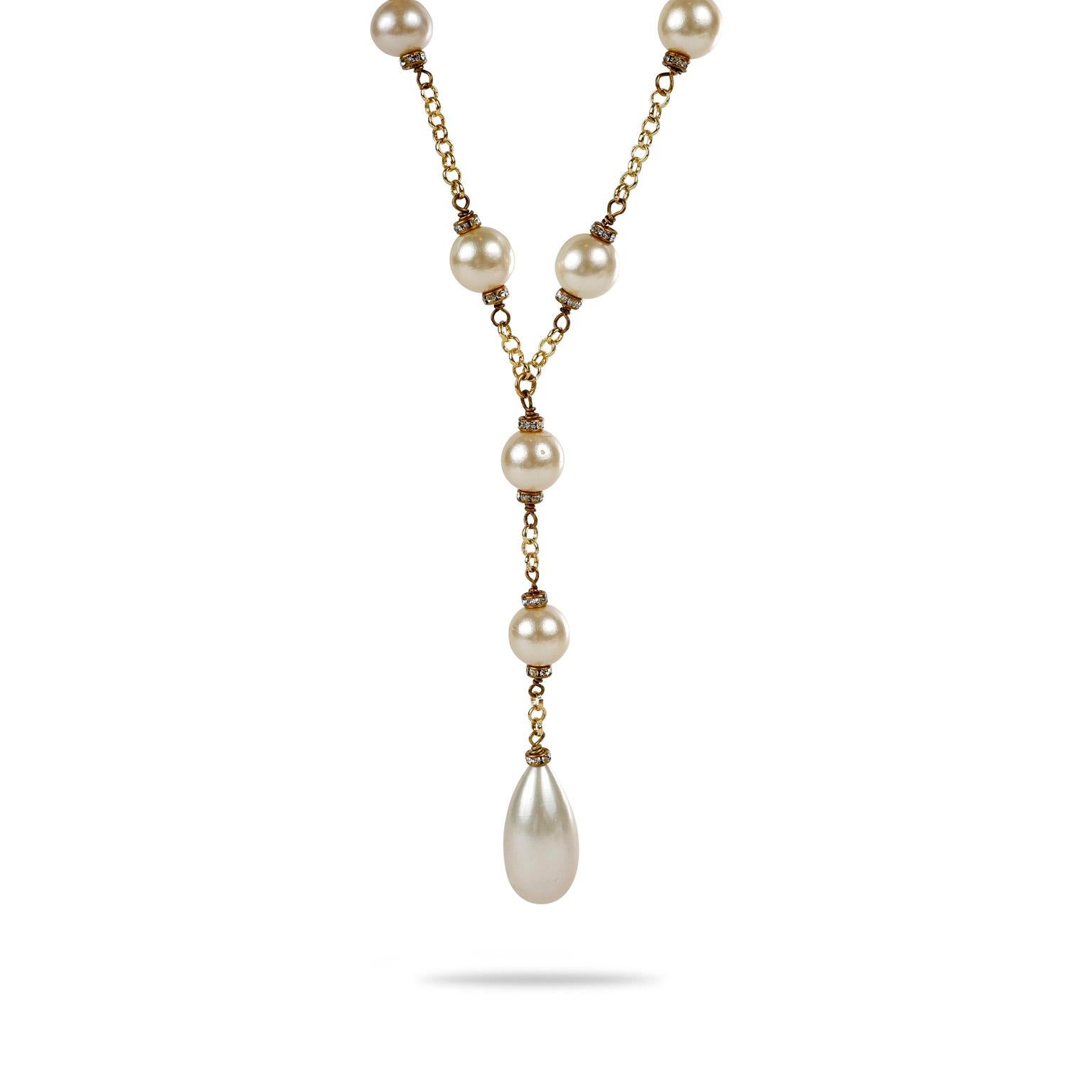 This authentic Chanel Pearl Lariat Necklace is in excellent vintage condition from the 1980’s.  24 karat gold plated chain with faux pearls anchored by tiny crystals.  A large tear drop shaped faux pearl dangles delicately down the center. Made in