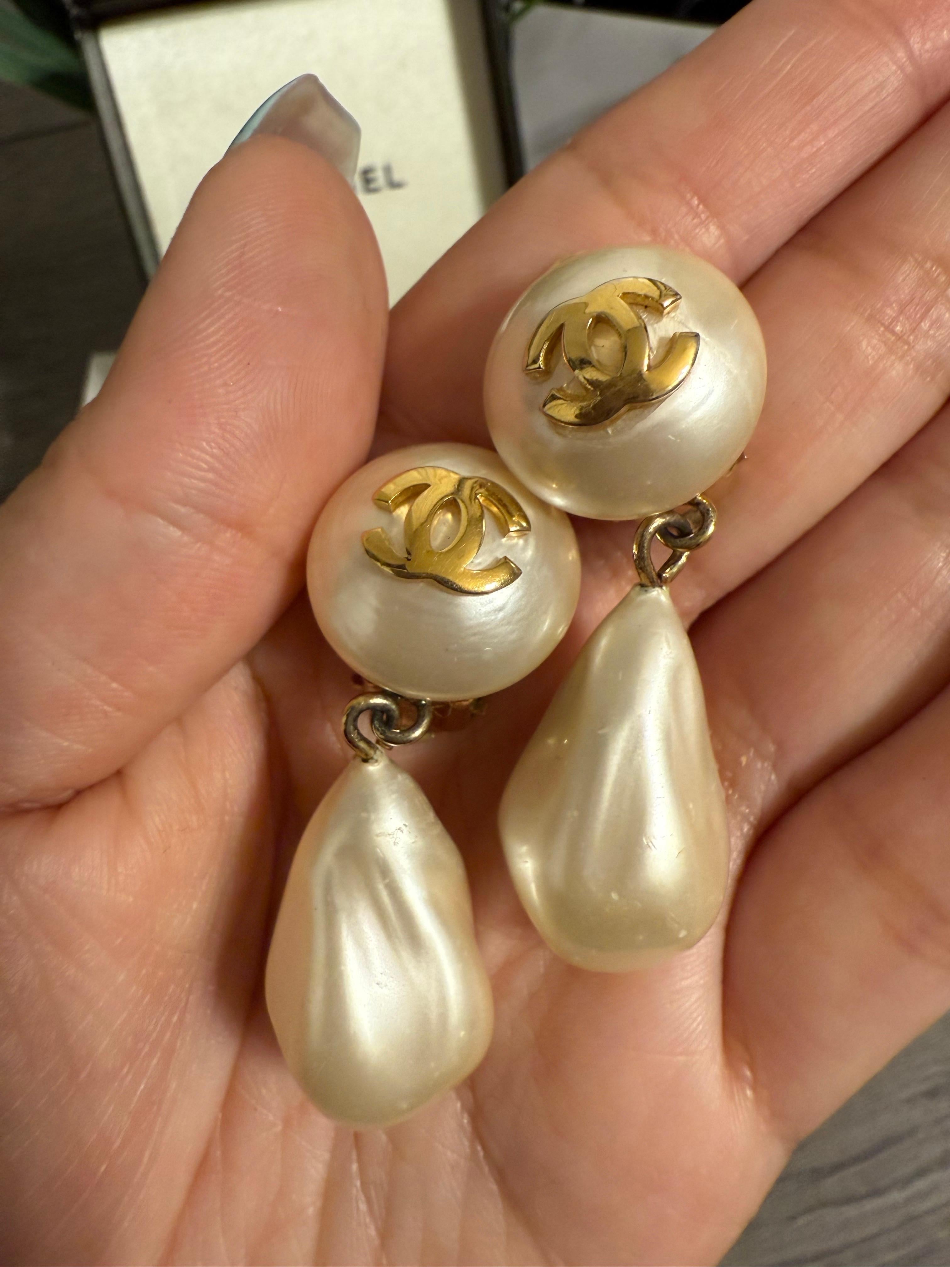 Pendientes de clip vintage CHANEL con logotipo CC dorado y gota de perla de imitación de estilo barroco. Estos pendientes clásicos son una pieza intemporal de la elegancia icónica de Chanel.

Detalles:
Sello: CHANEL en relieve.
Ligero desgaste y