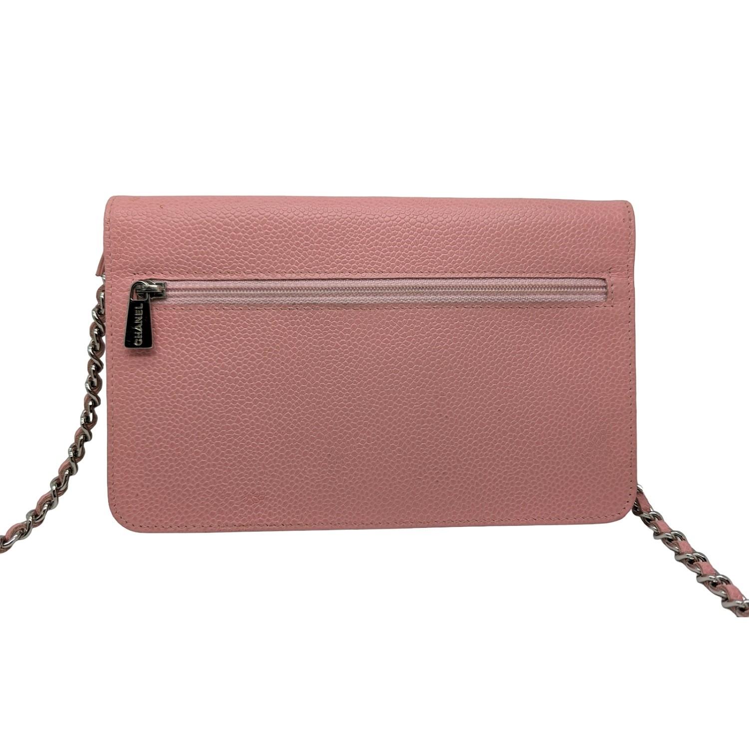 This stylish wallet is crafted of luxuriously textured caviar leather in pink, with a Chanel CC logo embossed on the front. The bag features a leather threaded silver chain-link shoulder strap and a crossover flap. This opens to a beige fabric and