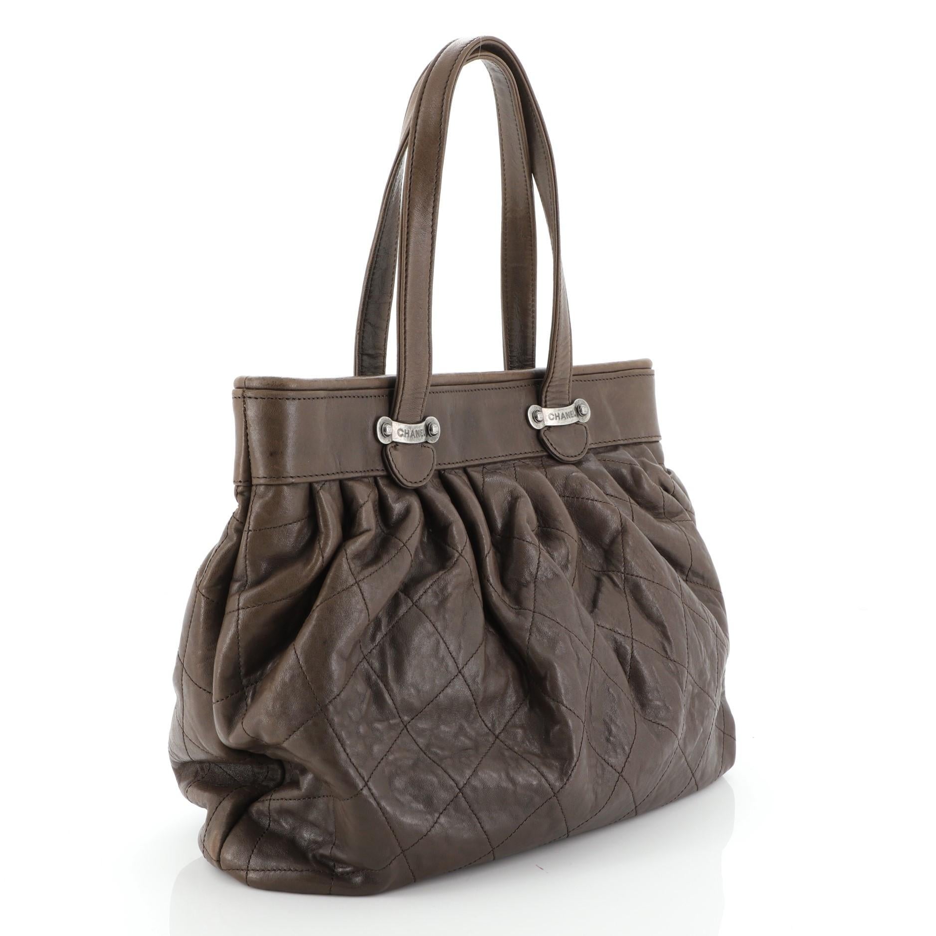 This Chanel Vintage Pleated Tote Quilted Calfskin Large, crafted from brown quilted calfskin leather, features flat leather straps, pleated silhouette and aged silver-tone hardware. Its cinch closure opens to a gray satin interior. Hologram sticker