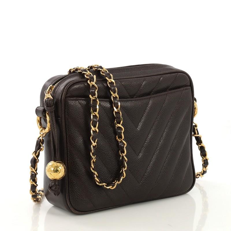 This Chanel Vintage Pocket Camera Bag Chevron Caviar Small, crafted from brown chevron caviar leather, features woven-in leather chain strap, exterior front slip pocket, and gold-tone hardware. Its zip closure opens to a brown leather interior with