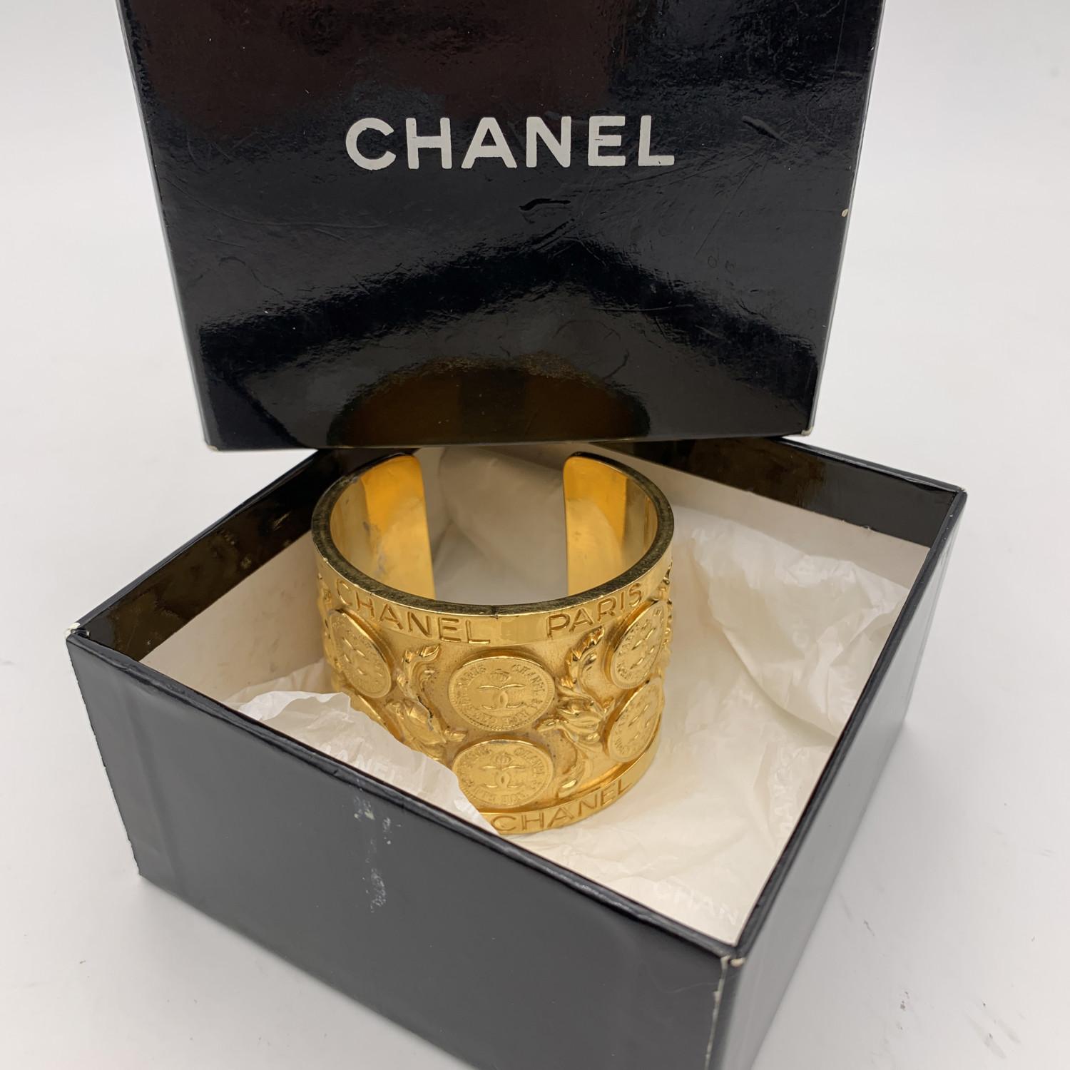 Beautiful rare vintage cuff bracelet by CHANEL. Gold metal bracelet with CC coin decorations and 'Chanel Paris' and 'Coco Chanel' writings. 'Chanel' basic signature engraved internally (according to the internal hallmark, the bracelet should date